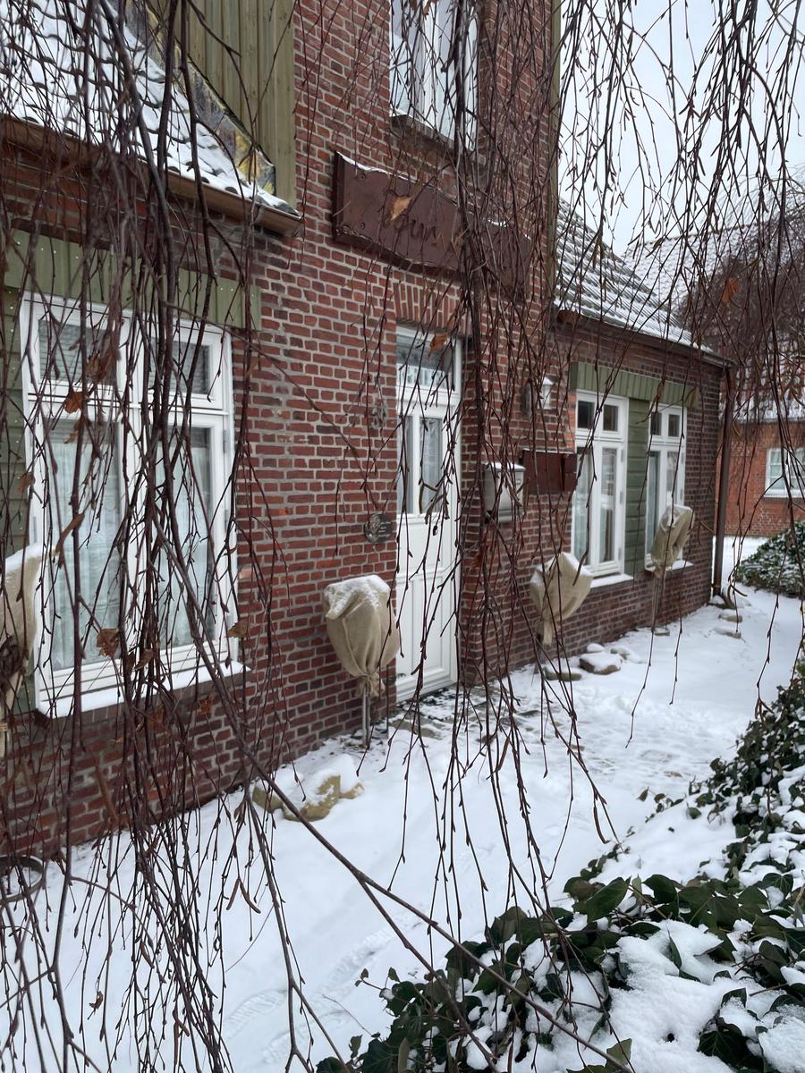 Rotes Backsteingebäude mit Schnee bedecktem Grundstück und weißen Fenstern.