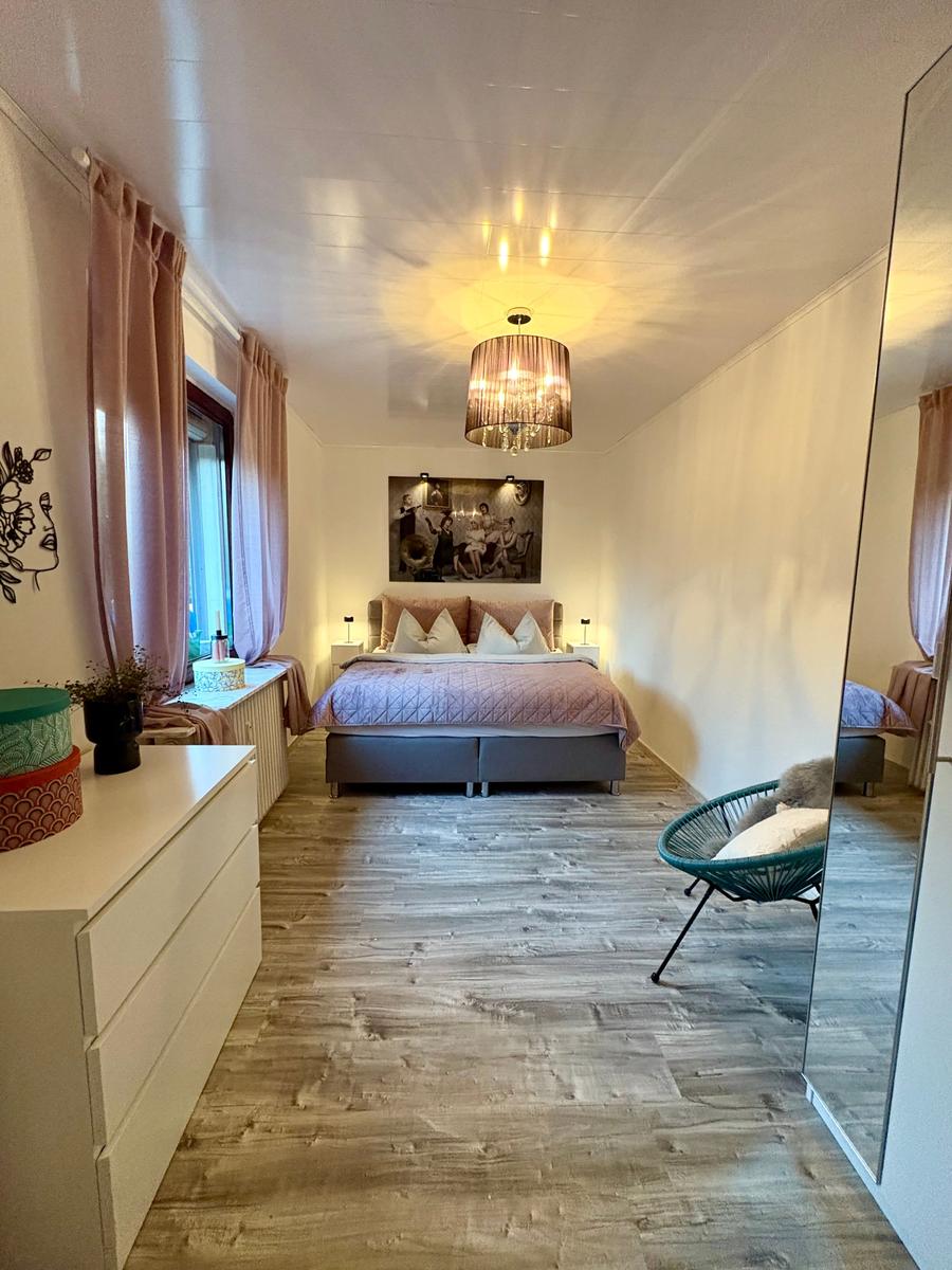 Schlafzimmer mit Bett, Decke, Lampe und Spiegel