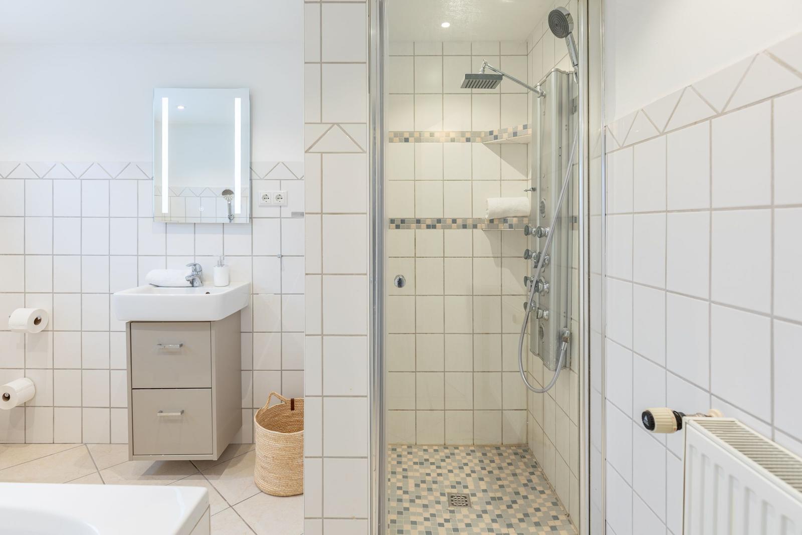 Badezimmer mit Dusche, Waschbecken und Spiegel.