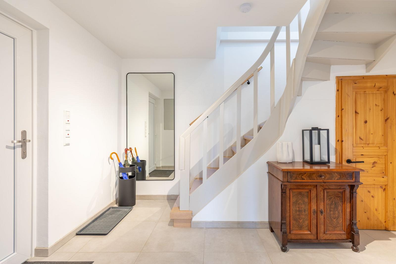 Eingang mit Treppe, Spiegel und Holzschränkchen
