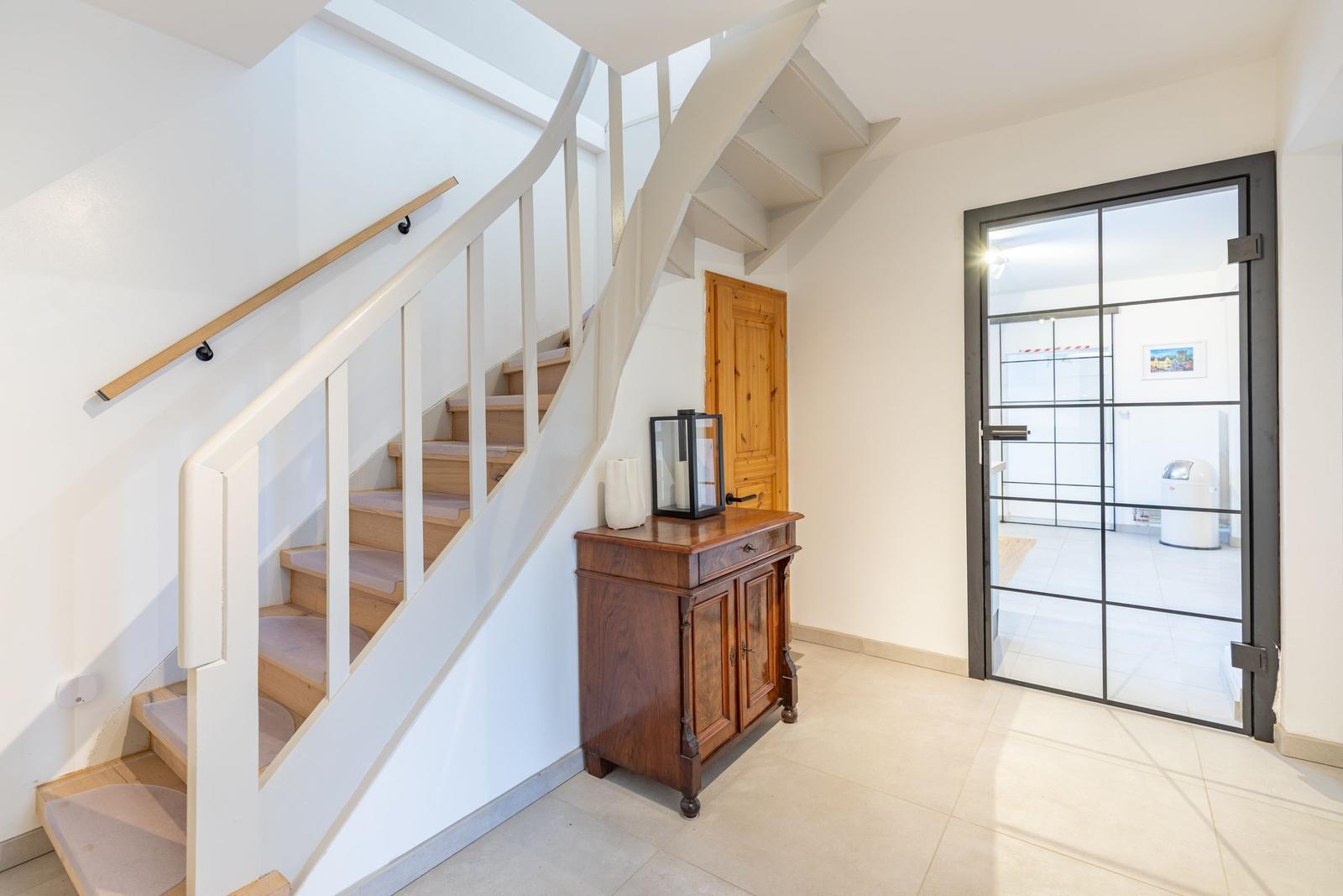 Eingang mit Treppe, Holzschrank und Glastür zum Flur.