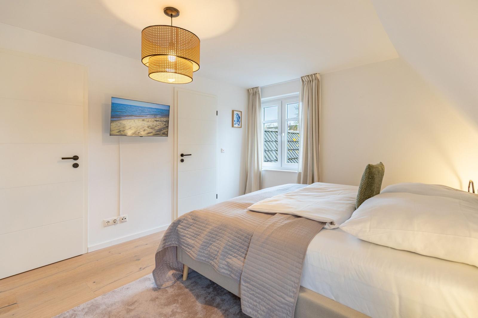 Schlafzimmer mit Bett, Fenster und Deckenleuchte.