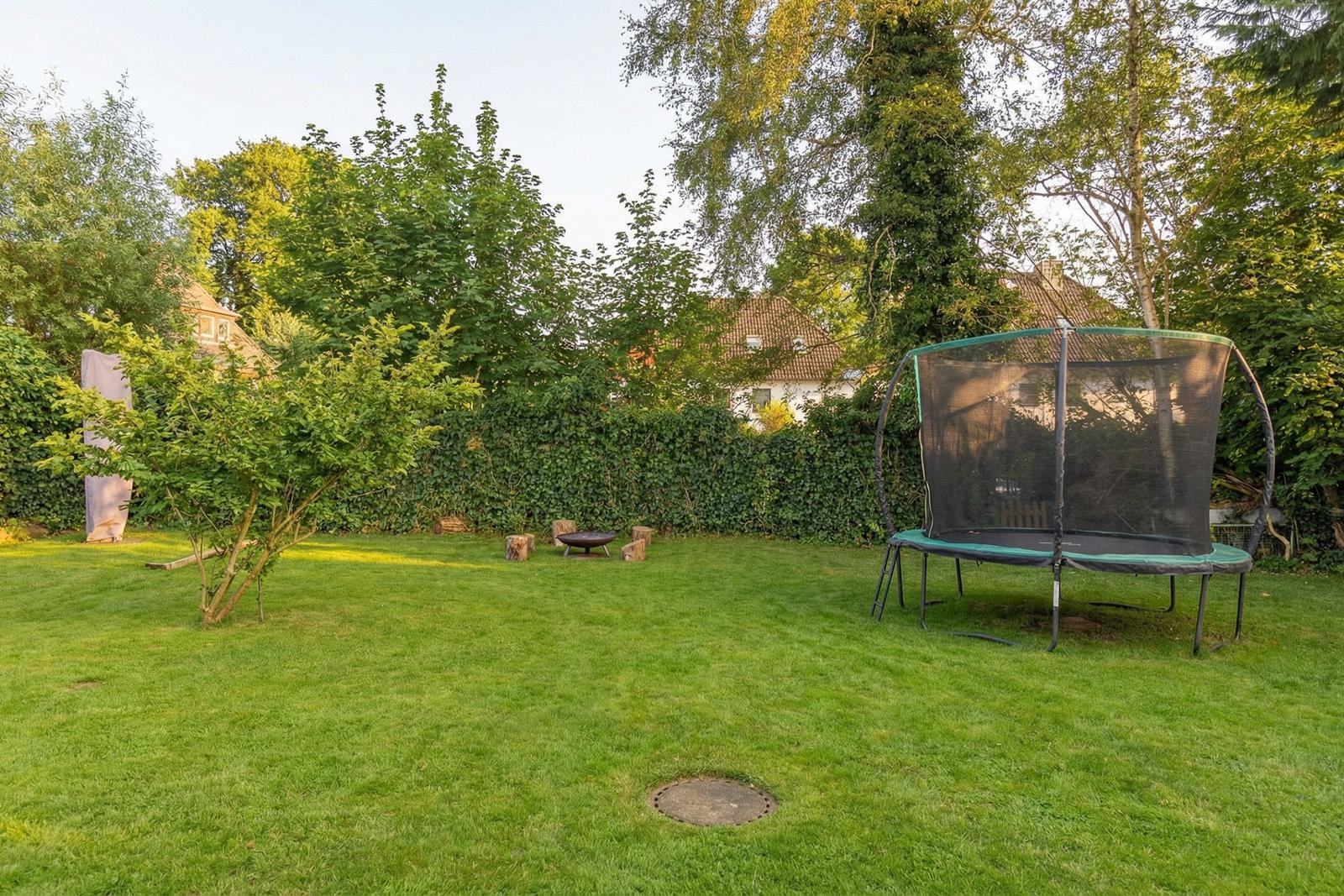 Garten mit Trampolin, Grillplatz und Rasenfläche.