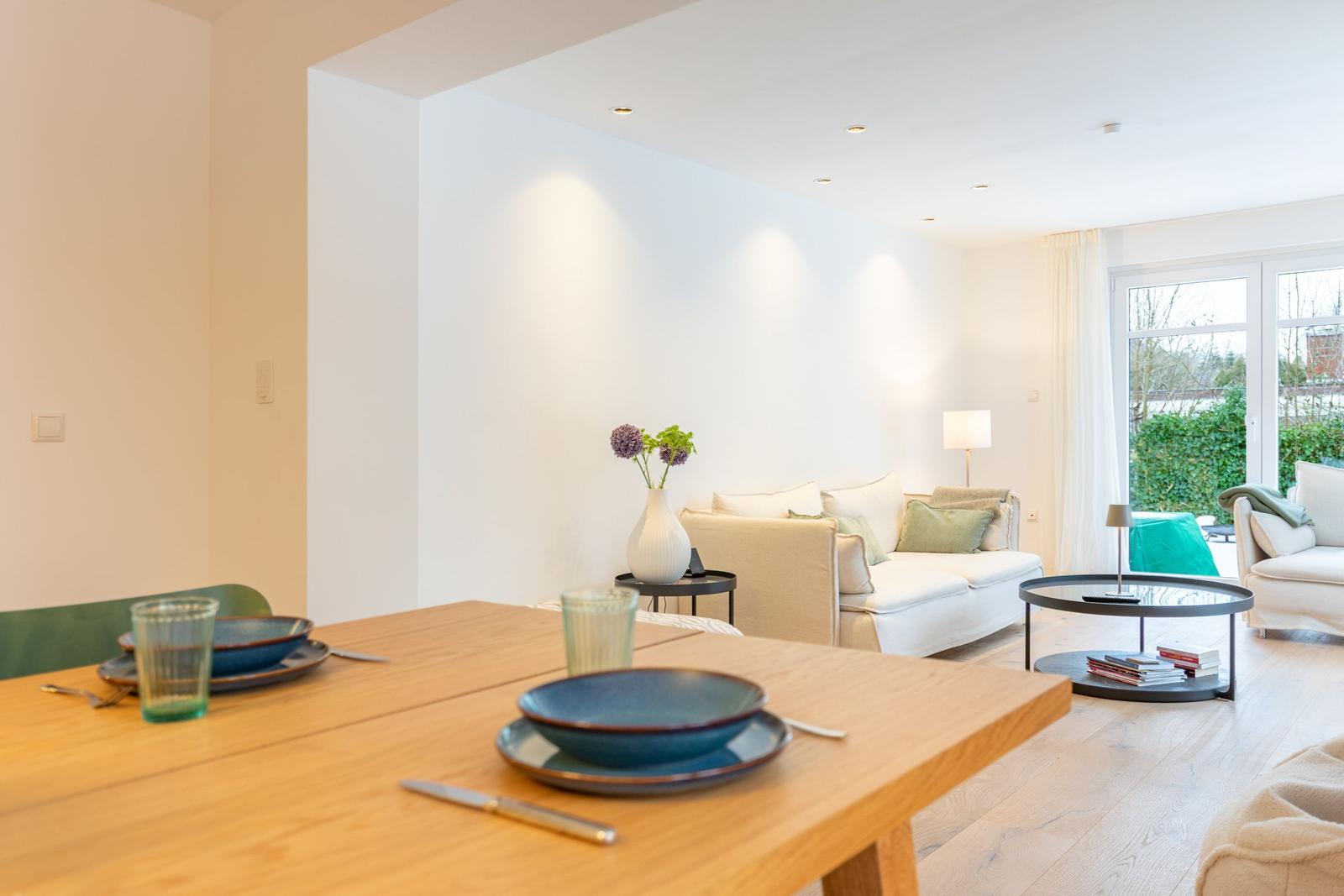 Essbereich mit Tisch und Stühlen, Wohnbereich mit Sofa und Couchtisch.