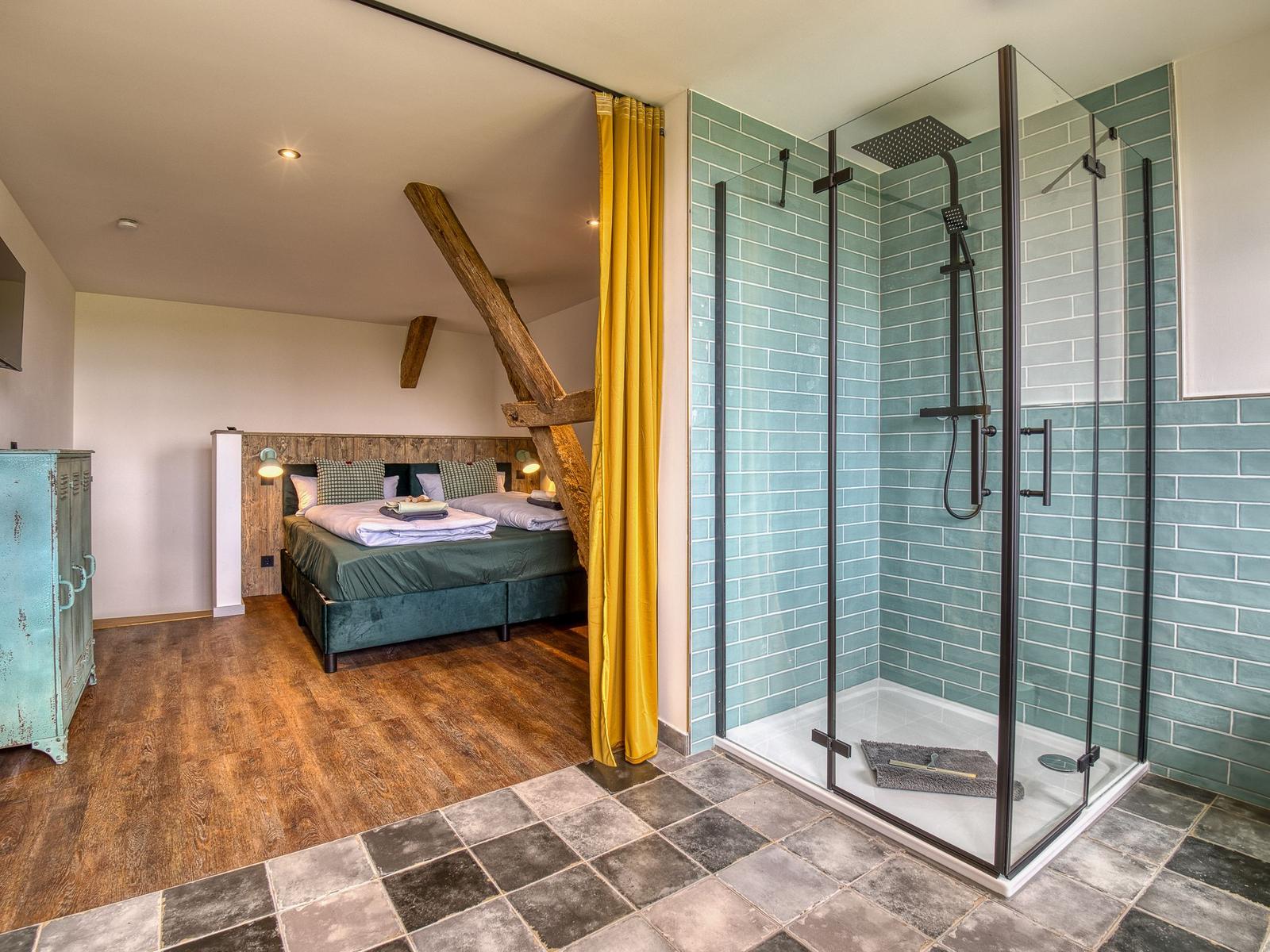 Schlafzimmer mit Doppelbett und Duschbad mit Glaswand und Fliesen.
