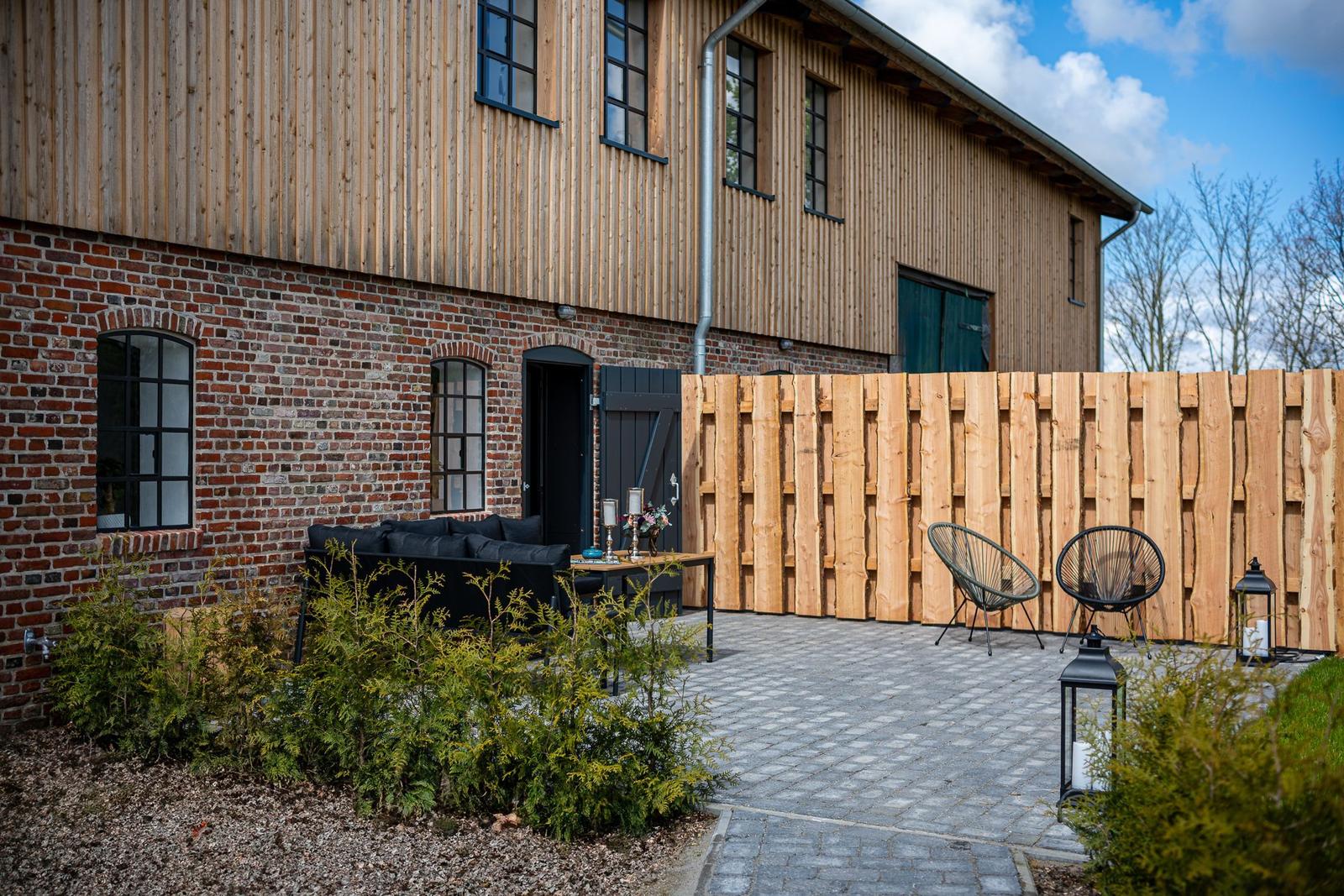 Hinterhof mit Sitzgelegenheiten und Holzzaun. Holz- und Ziegelhaus mit Fenstern.