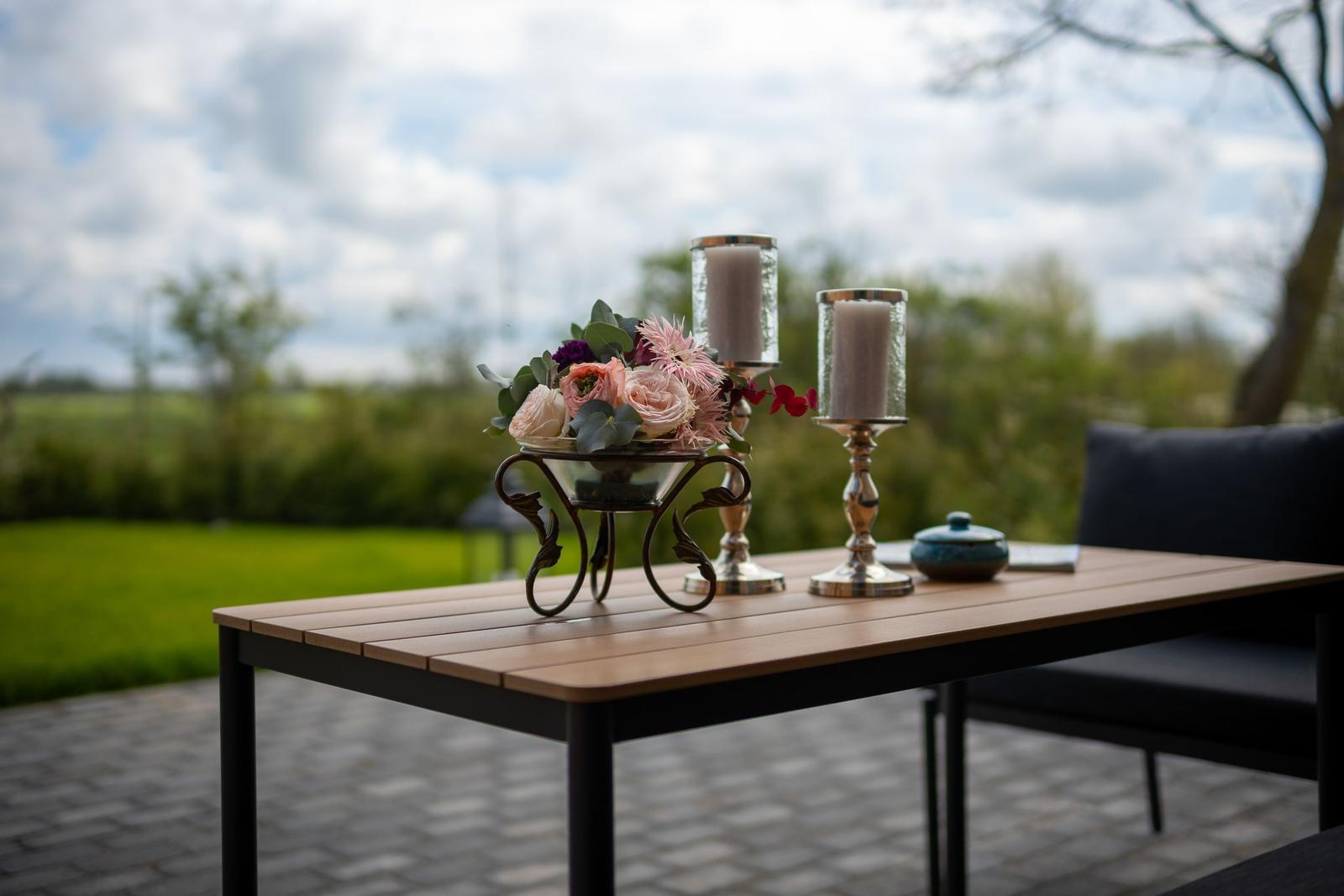 Hochwertiger Tisch mit Blumen und Kerzen auf Terrasse