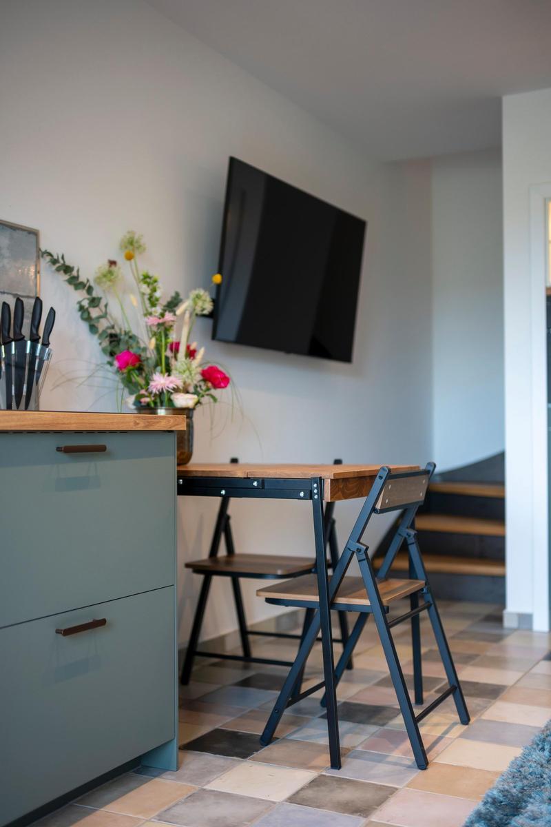 Küche mit Esstisch, Stühlen und Wandfernseher