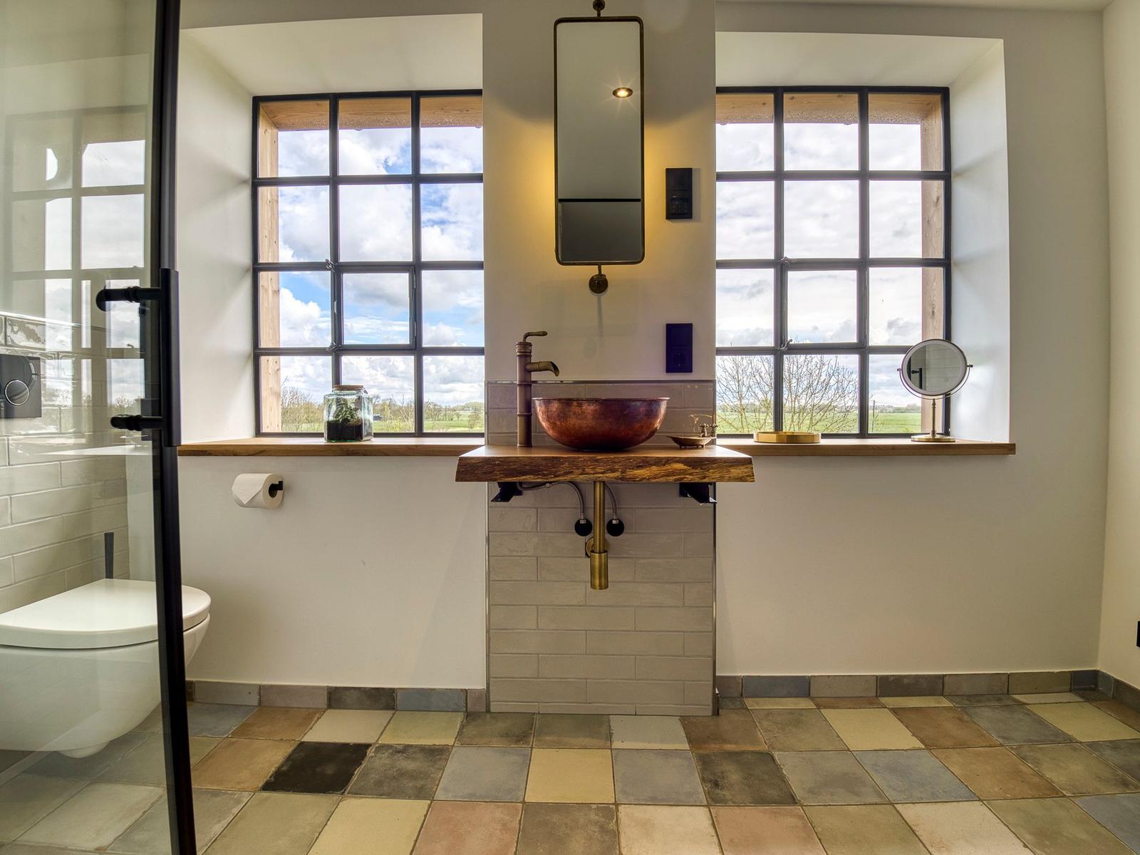 Bad mit Waschbecken, Fenstern und Dusche.