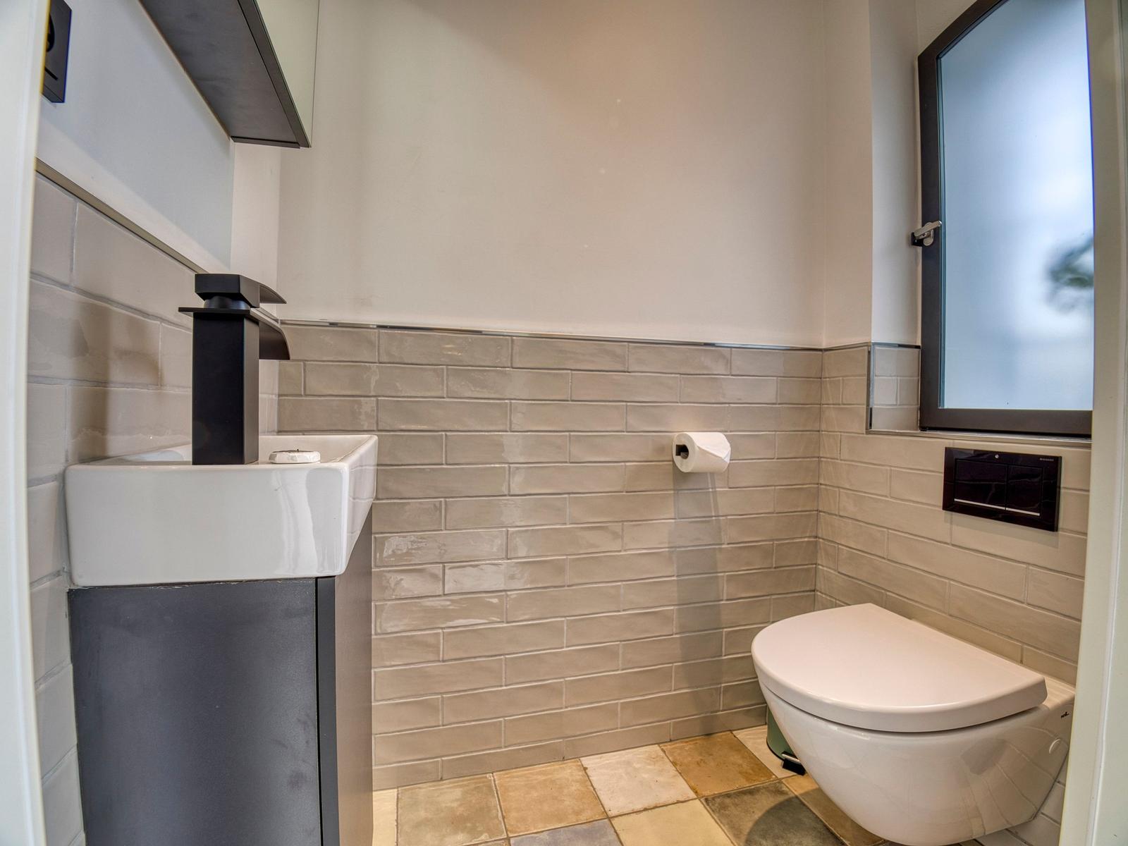 Badezimmer mit Waschbecken, Toilette und Fenster.