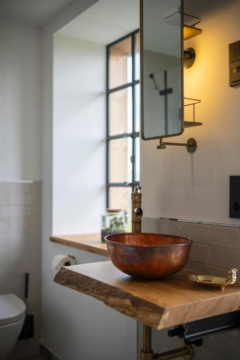Badezimmer mit Kupferspüle, Holzwaschtisch und Spiegelschrank