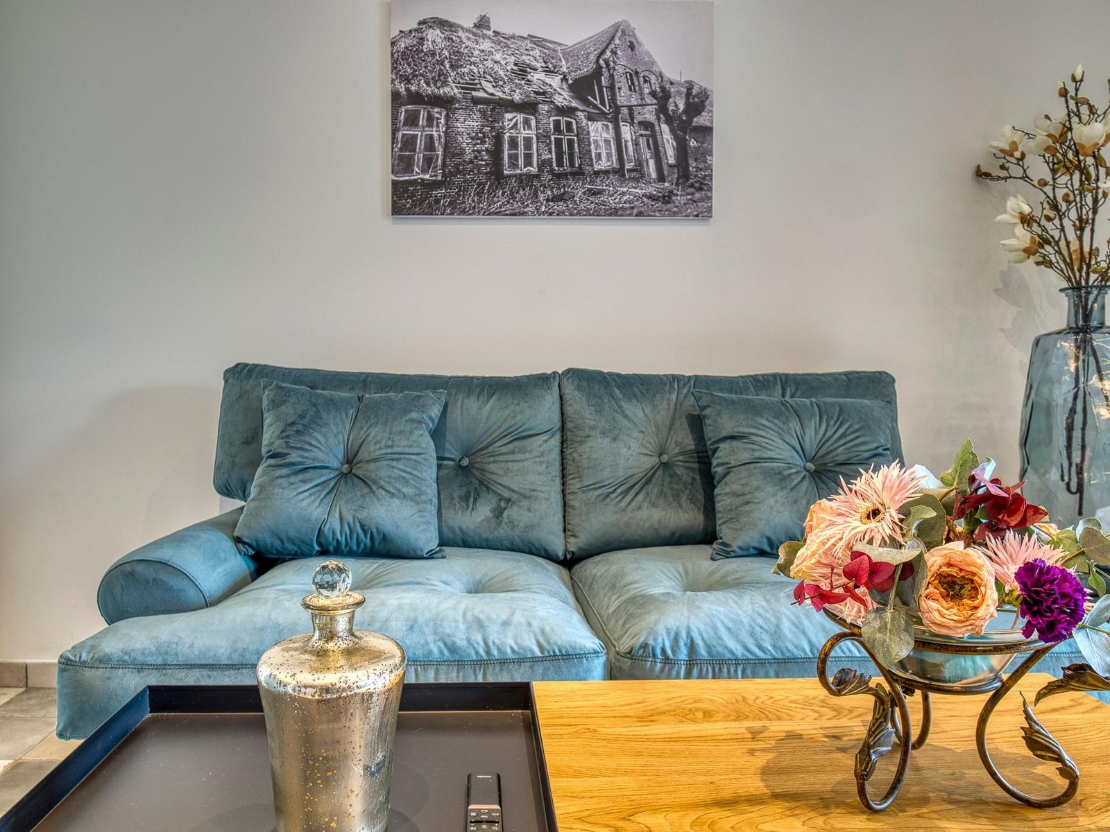 Ein Sofa mit Kissen, ein Tisch mit Blumen und eine Wanddekoration.