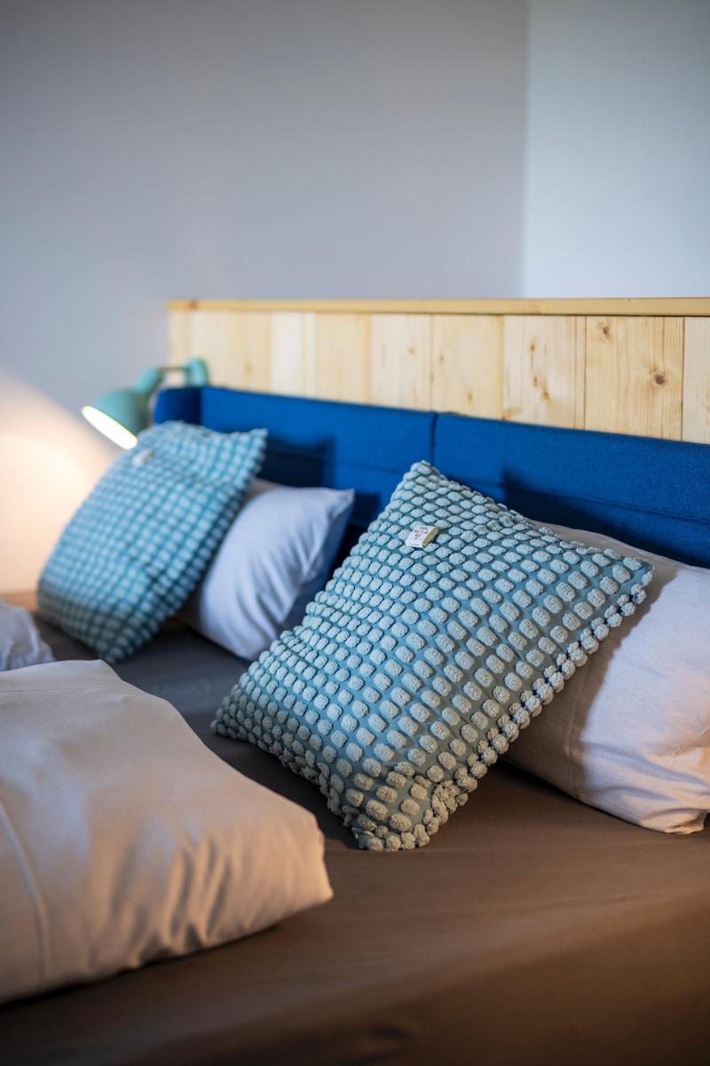 Bettkopfteil aus Holz und blauem Stoff mit Kissen und Nachttischlampe.