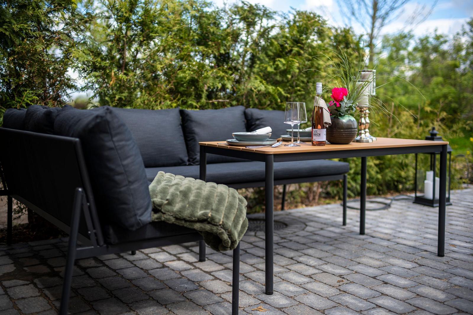 Außenbereich mit Sofa, Tisch und Getränken auf Steinplatten