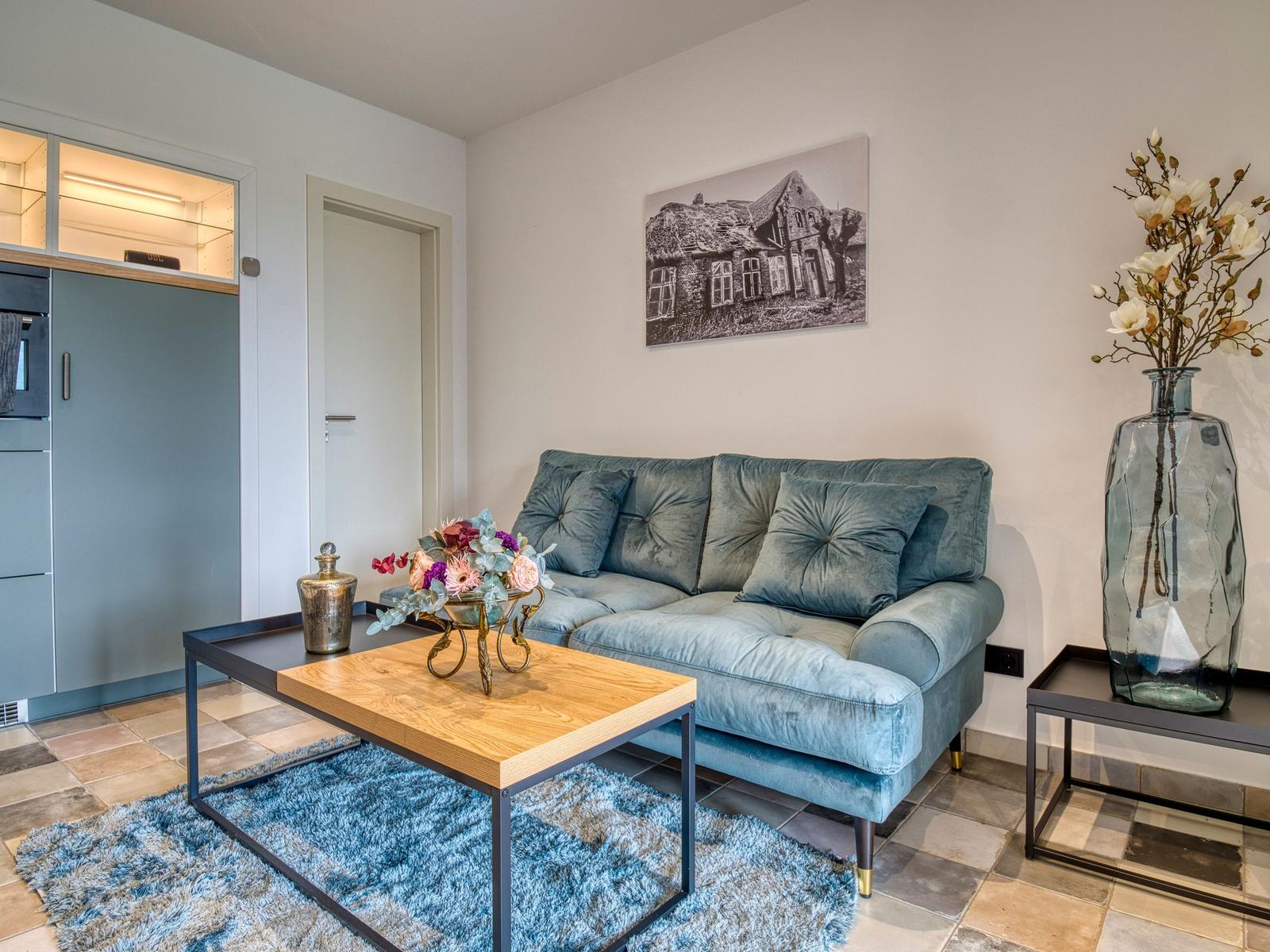 Ein Wohnbereich mit blauem Sofa, Holztisch und Wandbild.