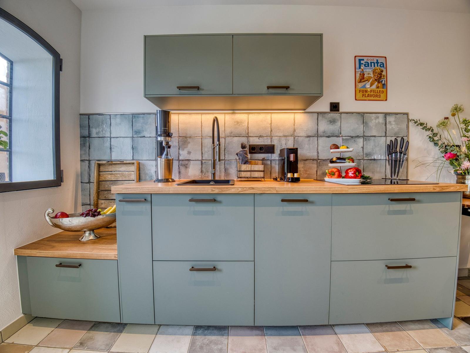 Küche mit hellblauen Schränken, Holzoberfläche und Steinrückwand.