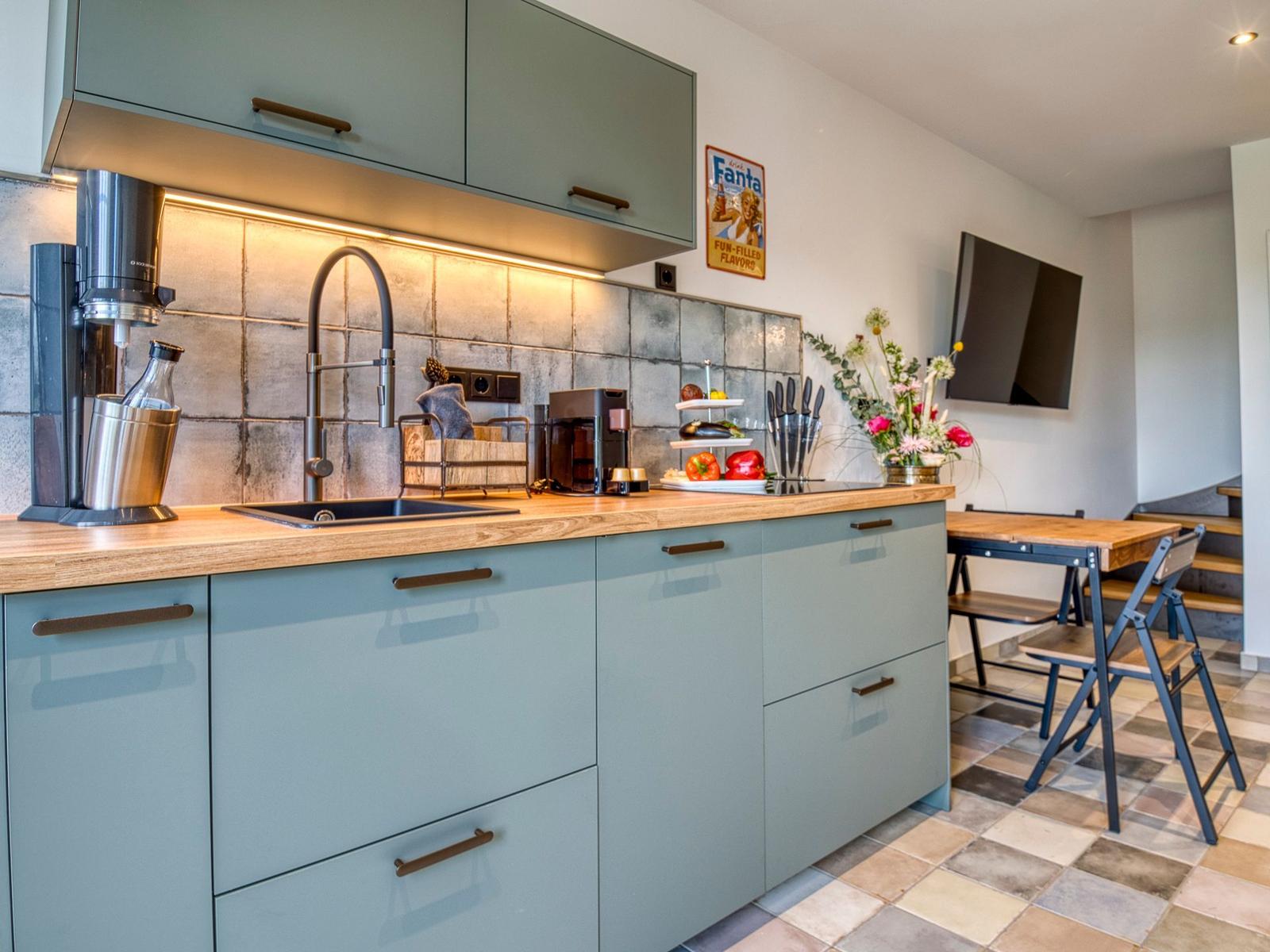 Küche mit Holzoberfläche, grauen Schränken und Küchenspüle.