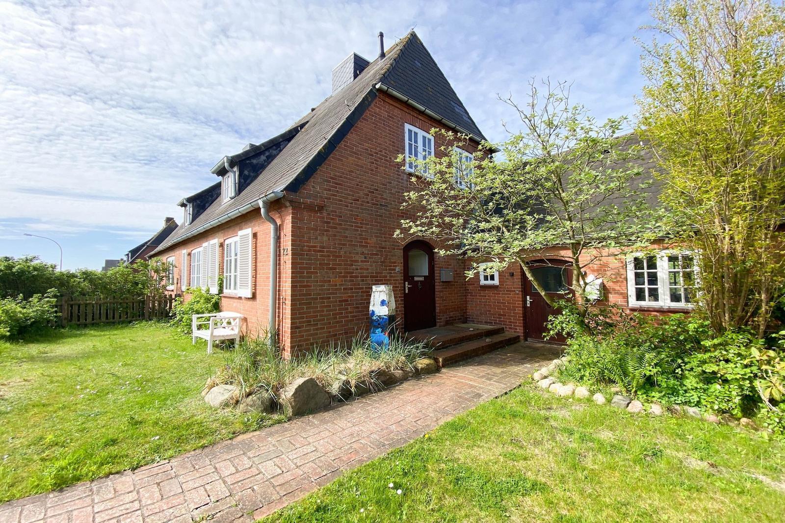 Rotes Backsteingebäude mit Garten und gepflastertem Weg.