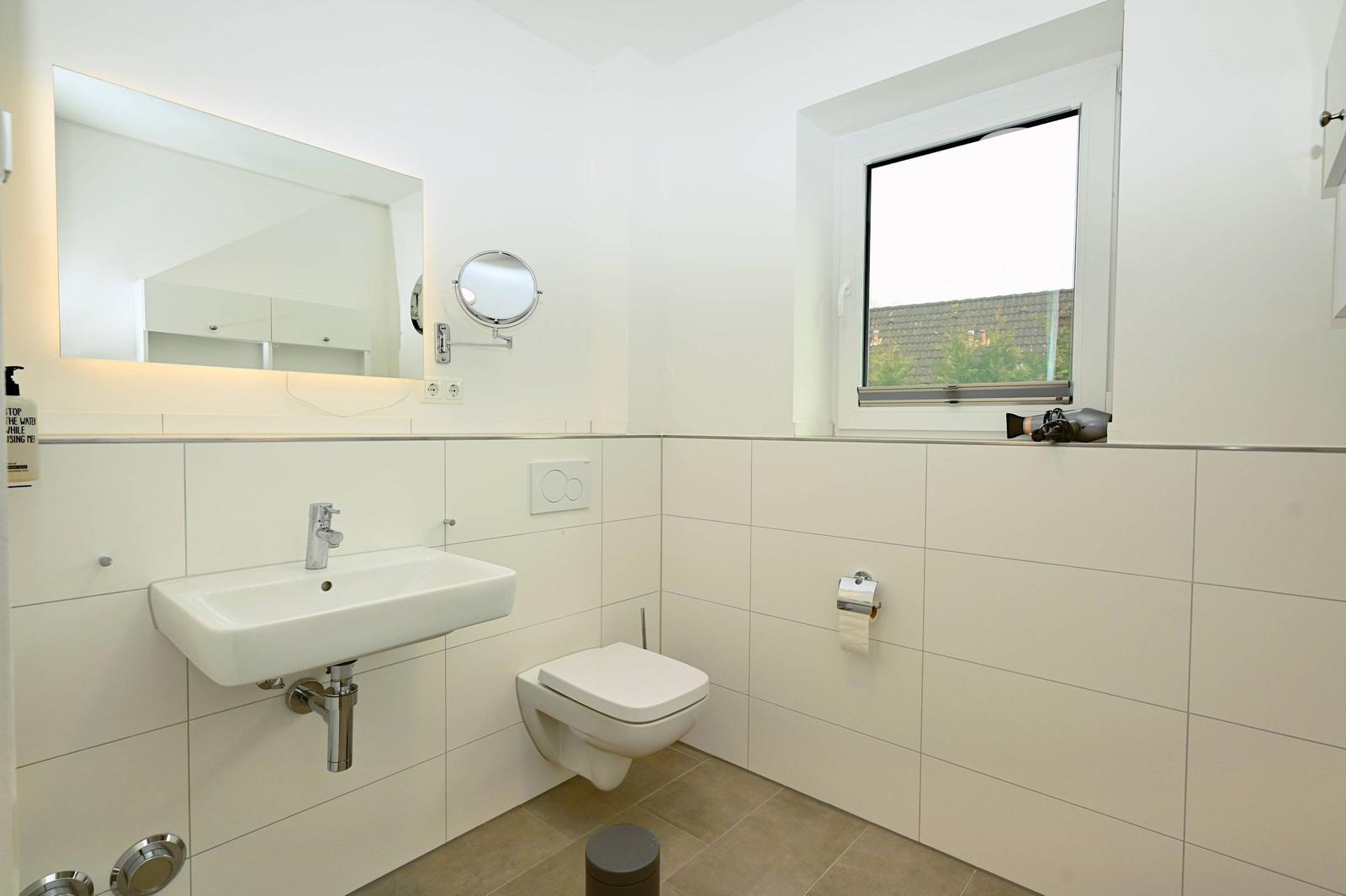 Badezimmer mit Waschbecken, Toilette und Fenster