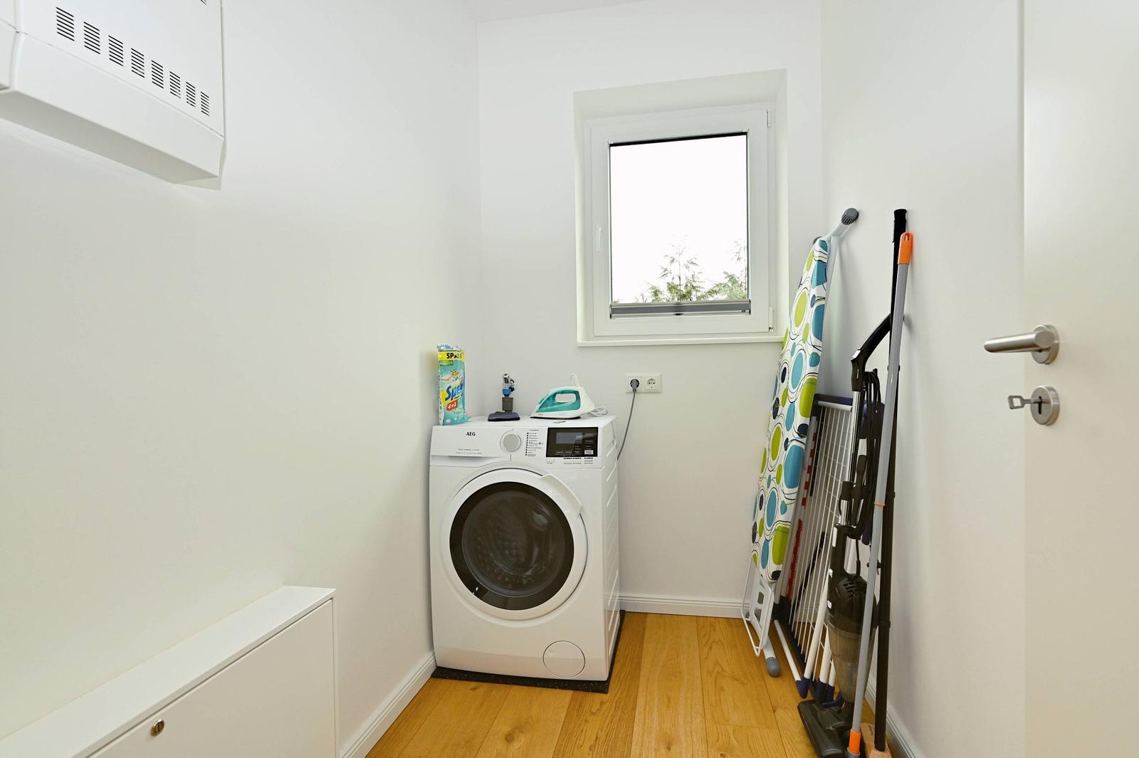Wäscherei mit Waschmaschine, Fenster und Reinigungsmitteln.