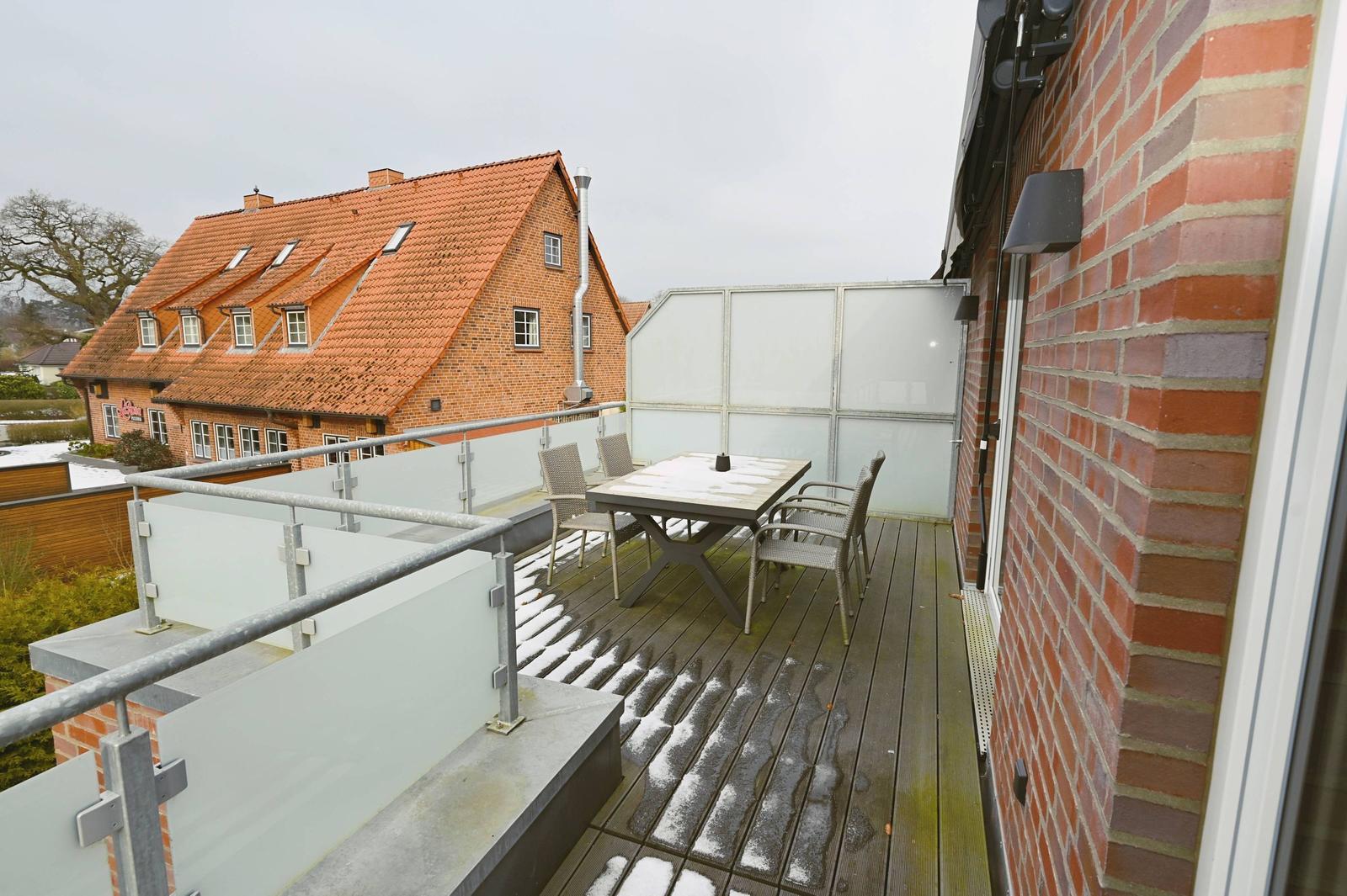 Terrasse mit Tisch und Stühlen, Blick auf ein roofgedecktes Haus.