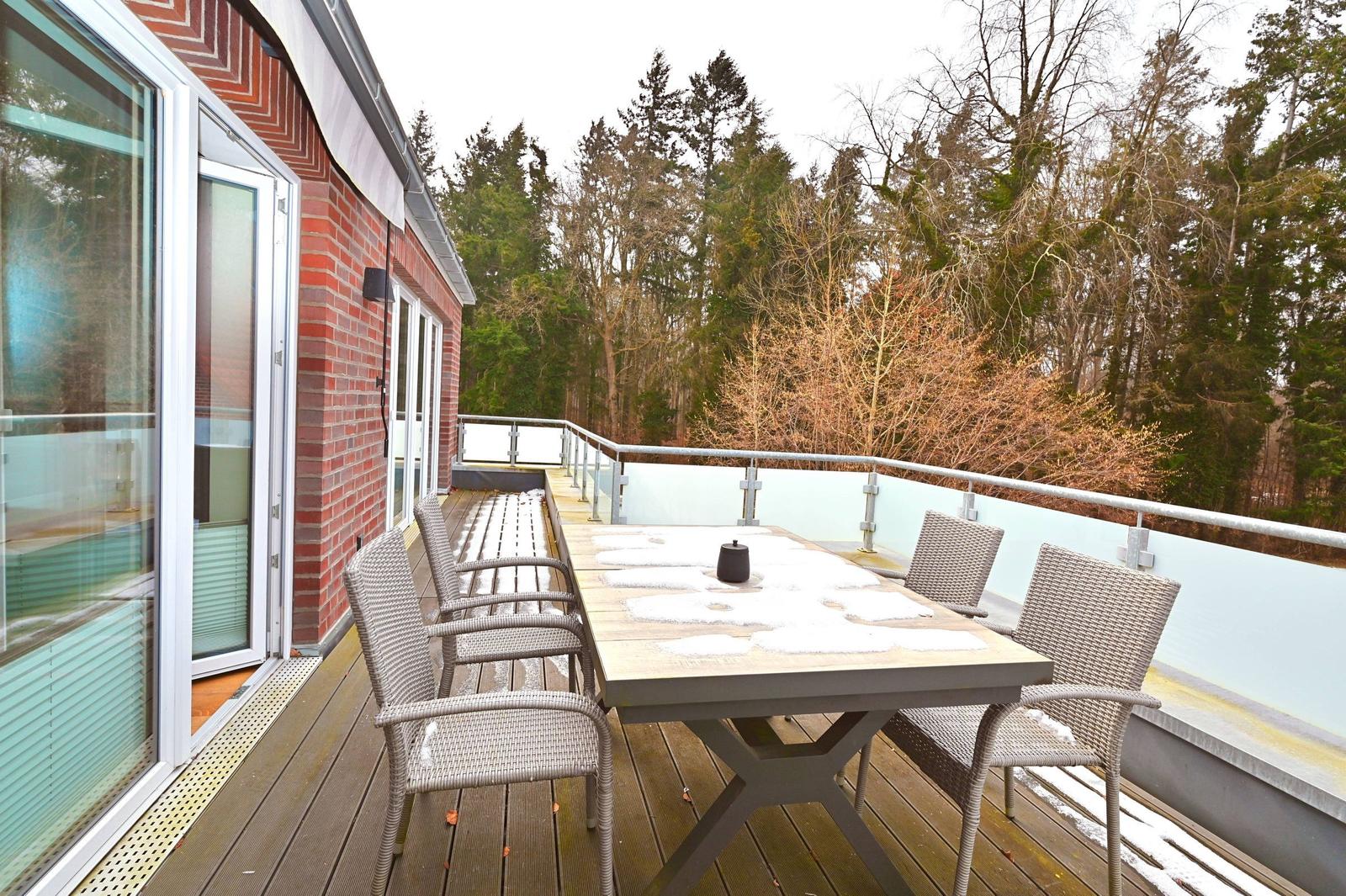 Terrasse mit Tisch und Stühlen, Blick in den Wald, teilweise schneebedeckt