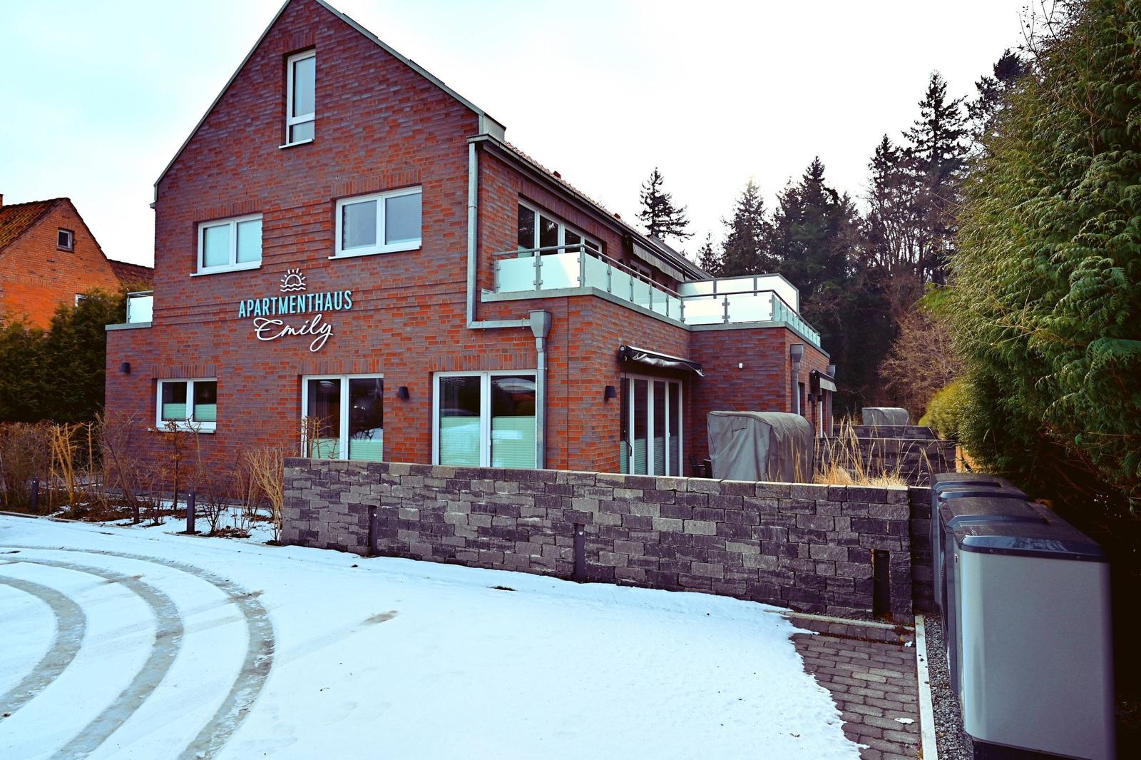 Apartmenthaus Emily mit Balkon, Schnee und Steinmauer.
