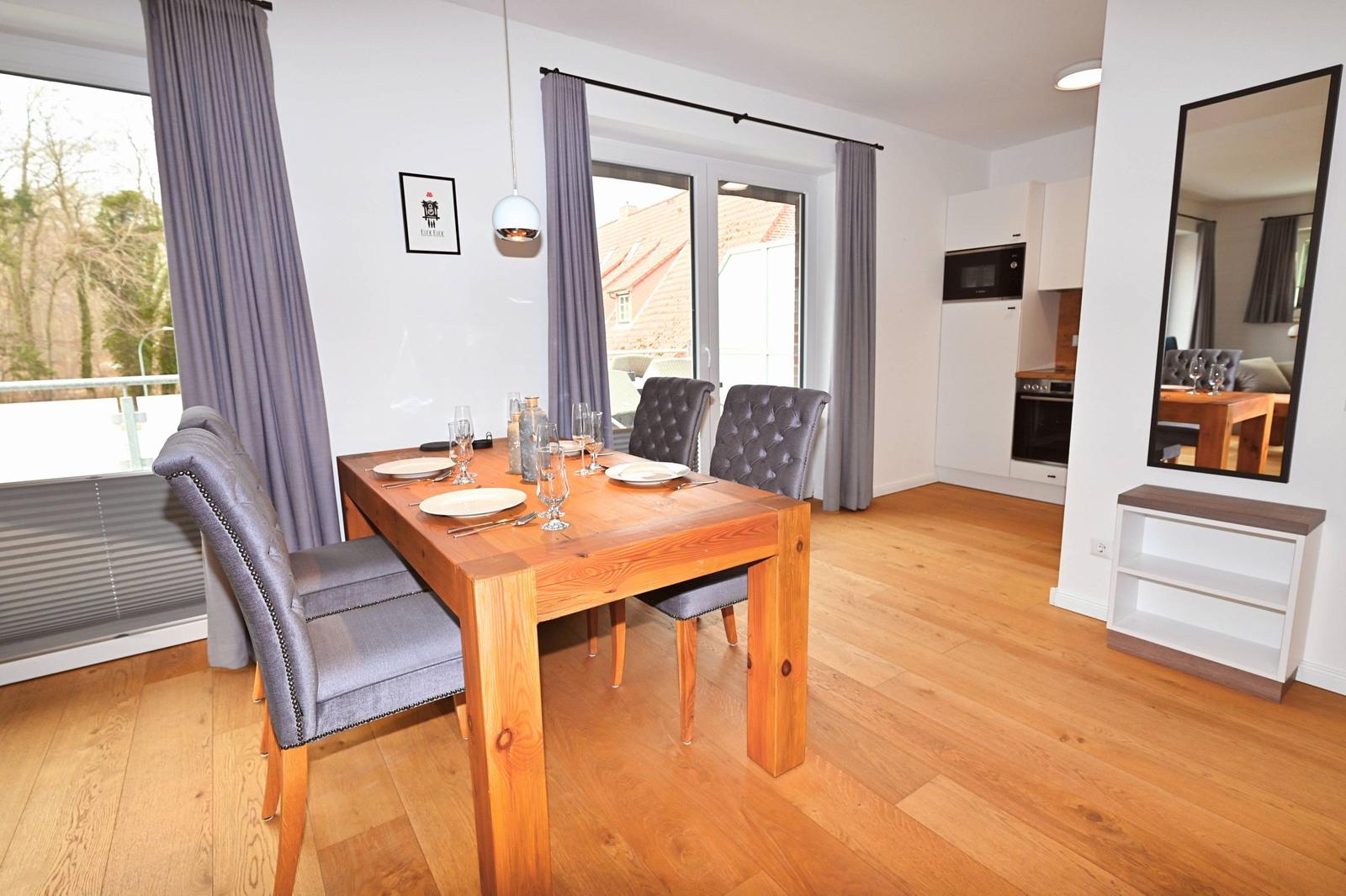 Esszimmer mit Holztisch, Stühlen und Blick auf Balkon