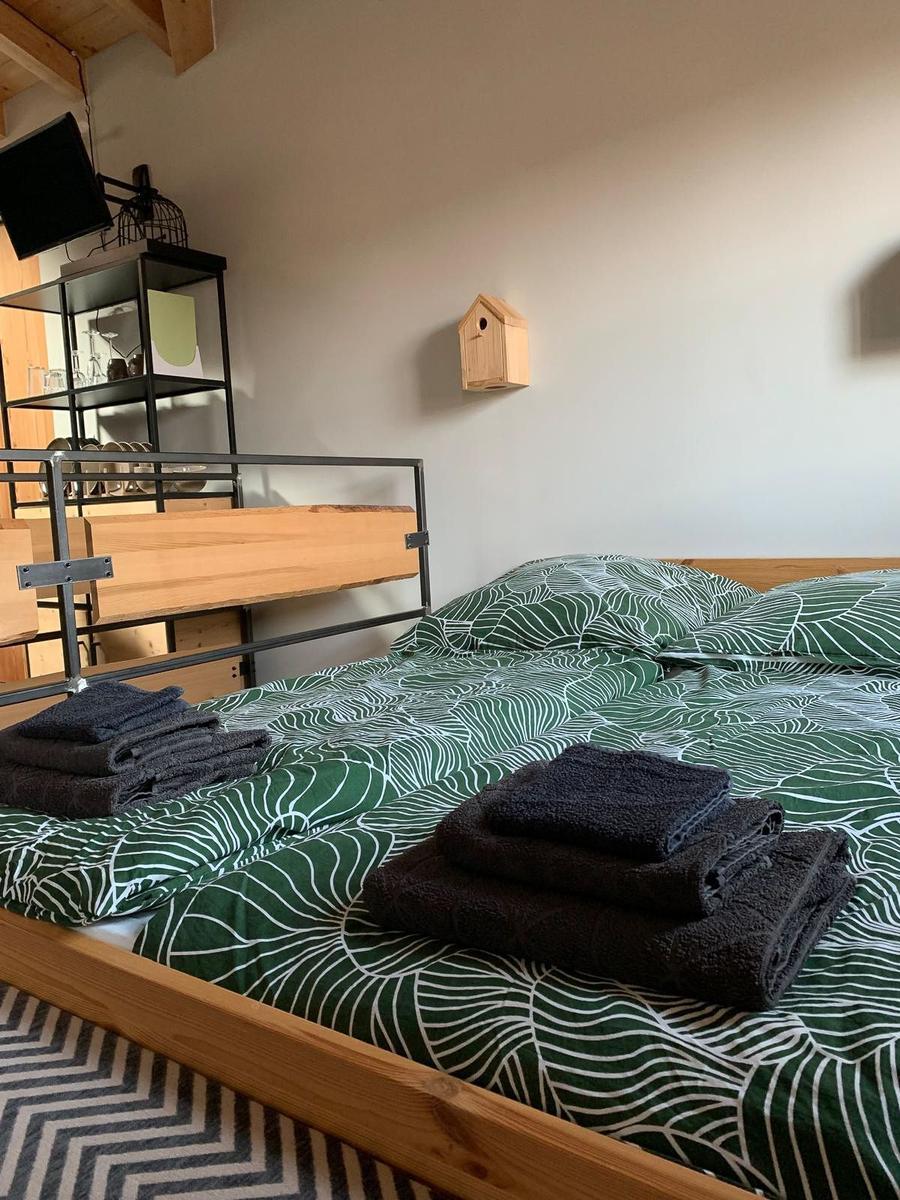 Doppelbett mit grün-weißem Bettbezug und gefalteten Handtüchern.