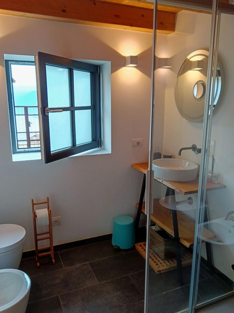 Badezimmer mit Dusche, Waschbecken und Fenster mit Meerblick.