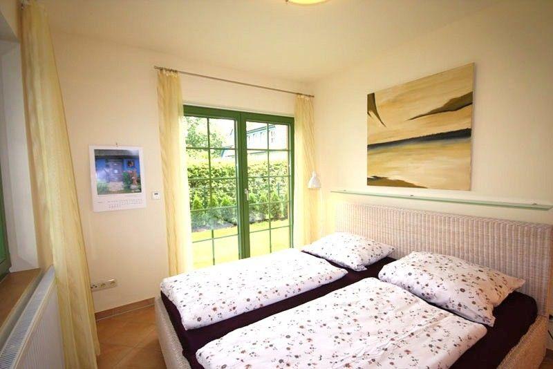 Zimmer mit Doppelbett, grünen Fenstern und Wandbild