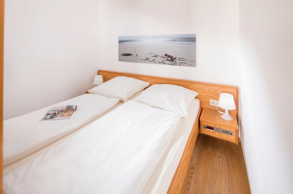 Ein Schlafzimmer mit Doppelbett, Holzrahmen und Nachttisch mit Lampe.