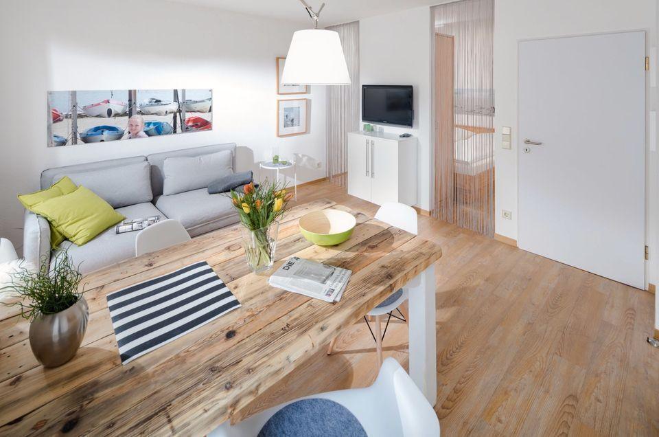 Wohn- und Essbereich mit Holztisch, Sofa und Fernseher.