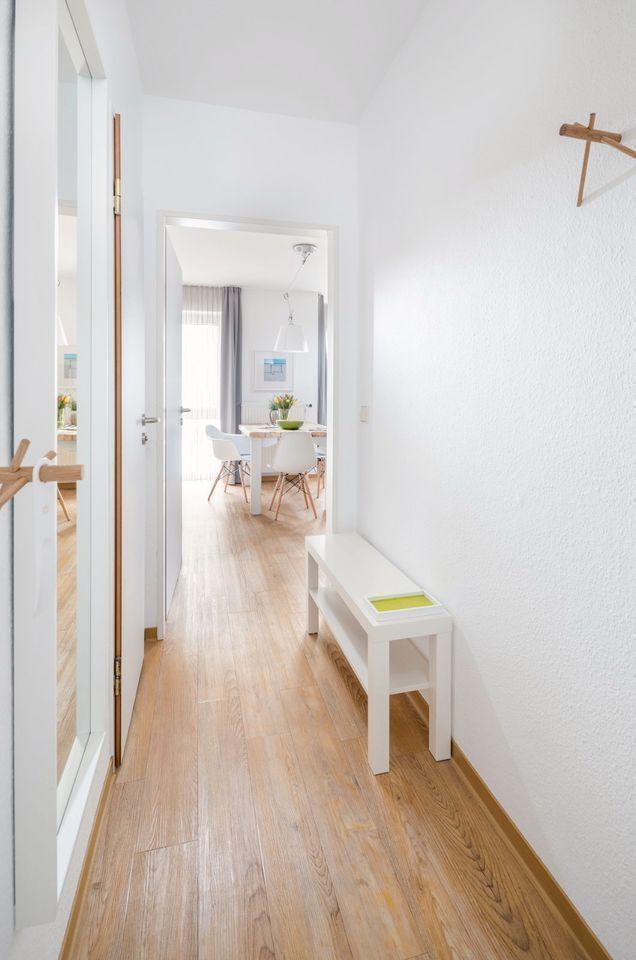 Flur mit Holzboden, weißer Bank und Blick in Esszimmer.