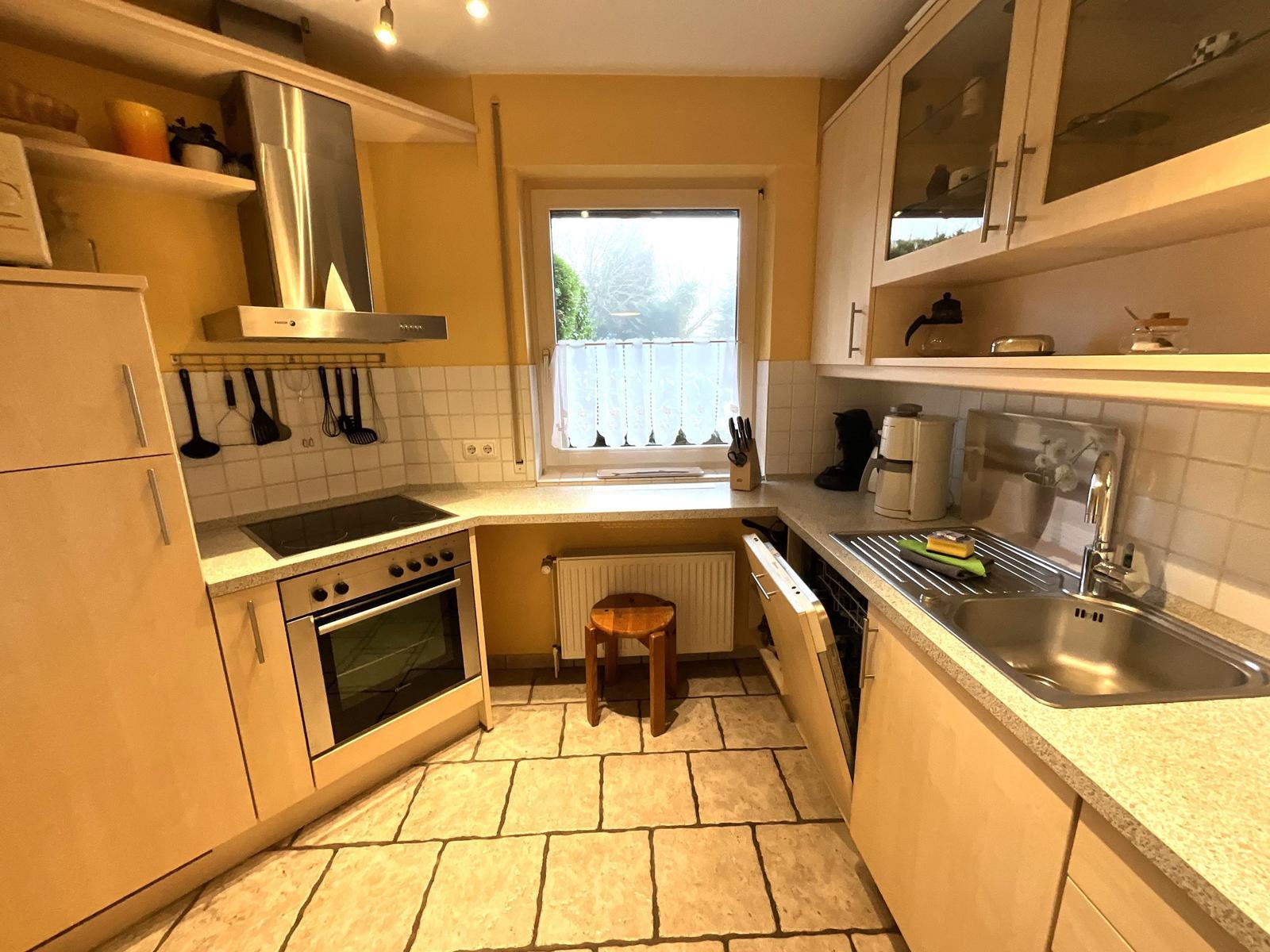 Küche mit Arbeitsplatten, Spüle, Herd und Fenster mit Blick.