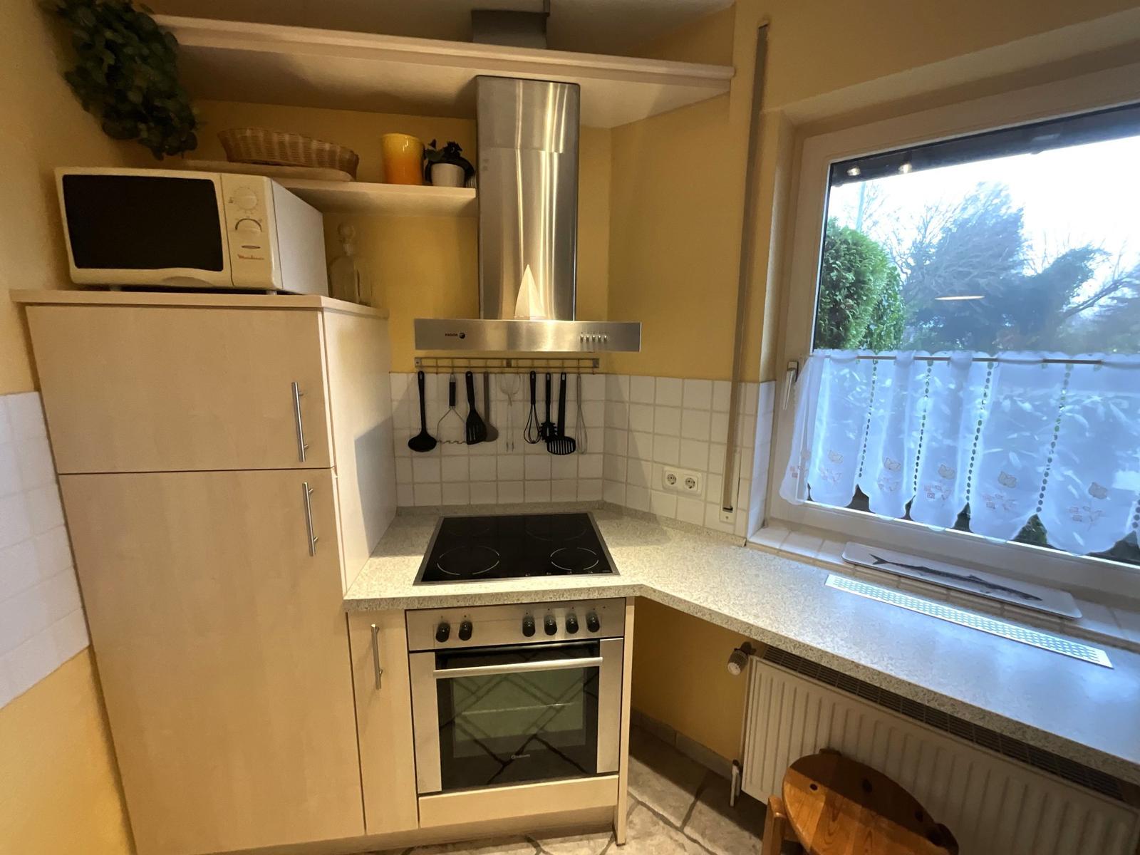 Küche mit Herd, Backofen, Dunstabzug und Fenster