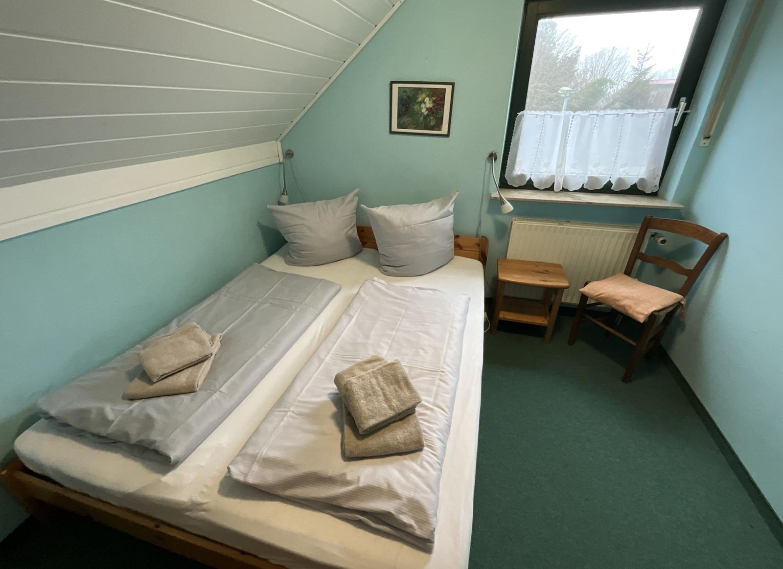 Ein Schlafzimmer mit einem Doppelbett, einem Stuhl und einem Fenster.