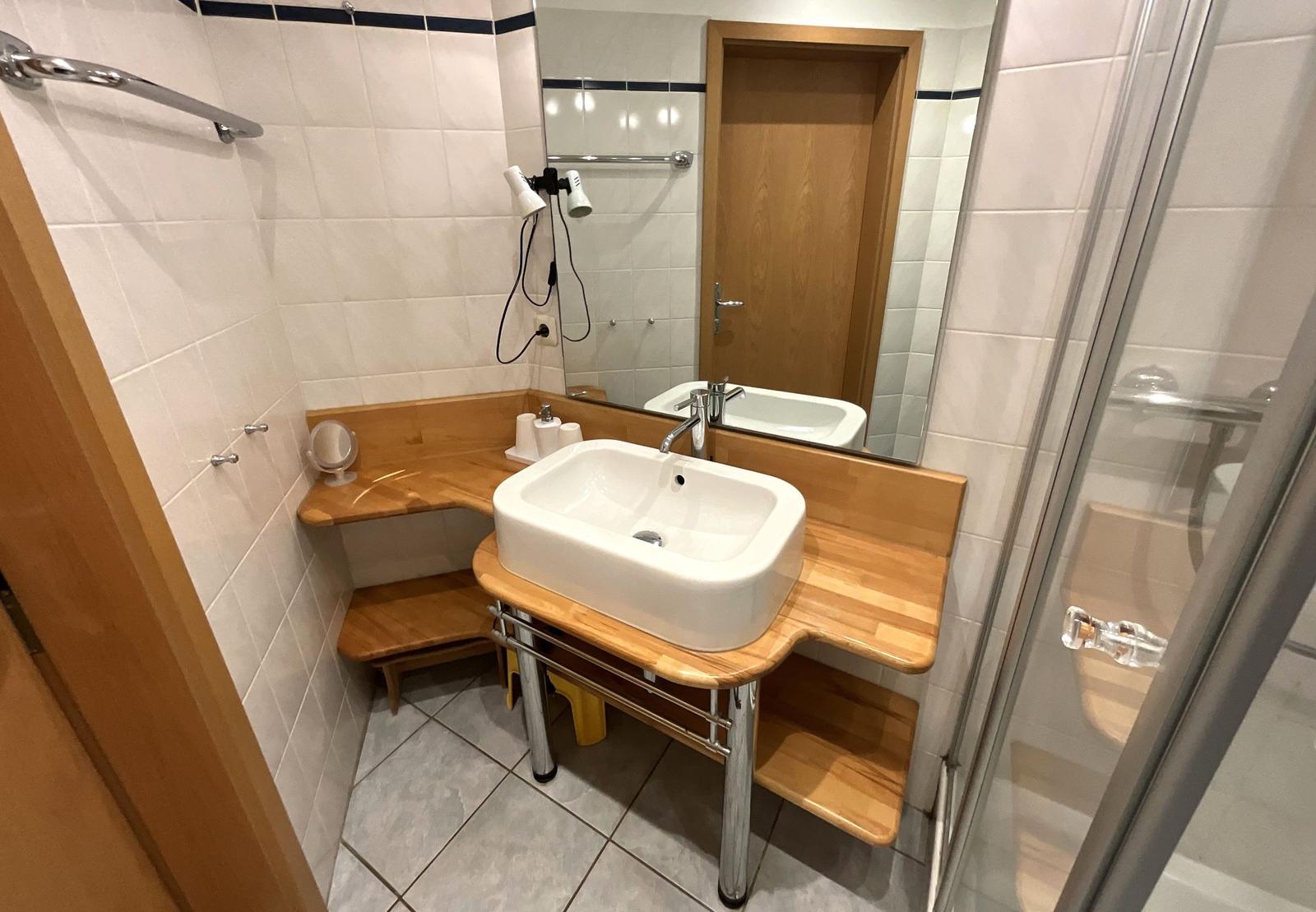 Badezimmer mit Waschbecken, Dusche und Spiegel.