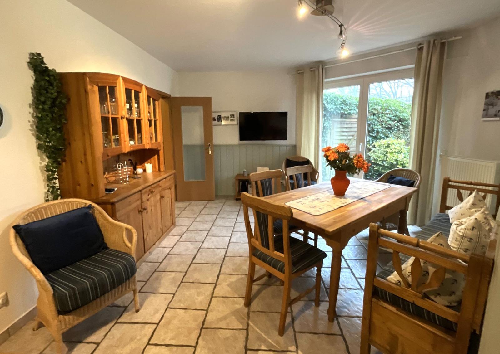 Esszimmer mit Holztisch, Stühlen und Küchenzeile. Durchgang zur Küche.