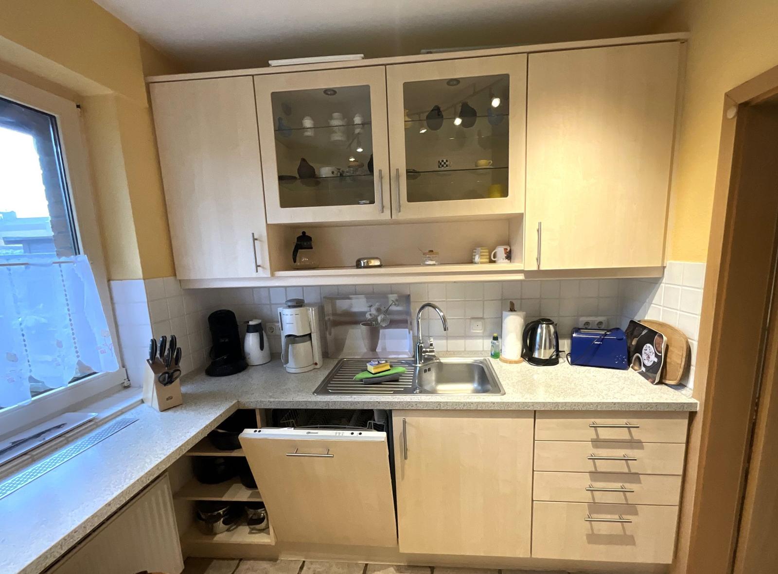 Küche mit hellen Schränken, Spüle und Fenster