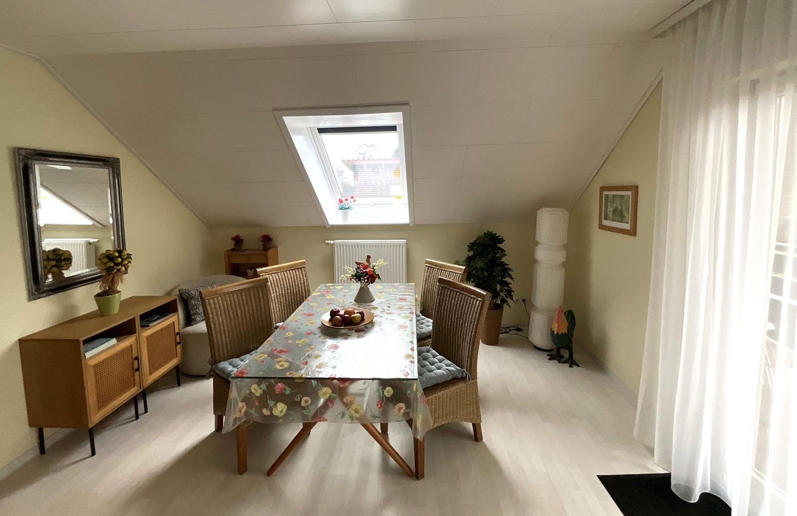 Esszimmer mit Tisch, Stühlen und Dachfenster. Holzfußboden und Wandspiegel.