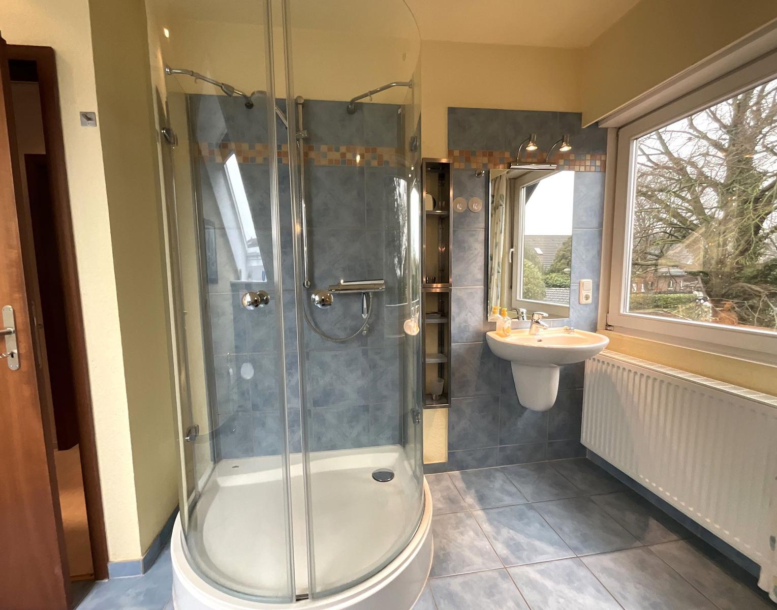 Badezimmer mit Dusche, Waschbecken und Fenster