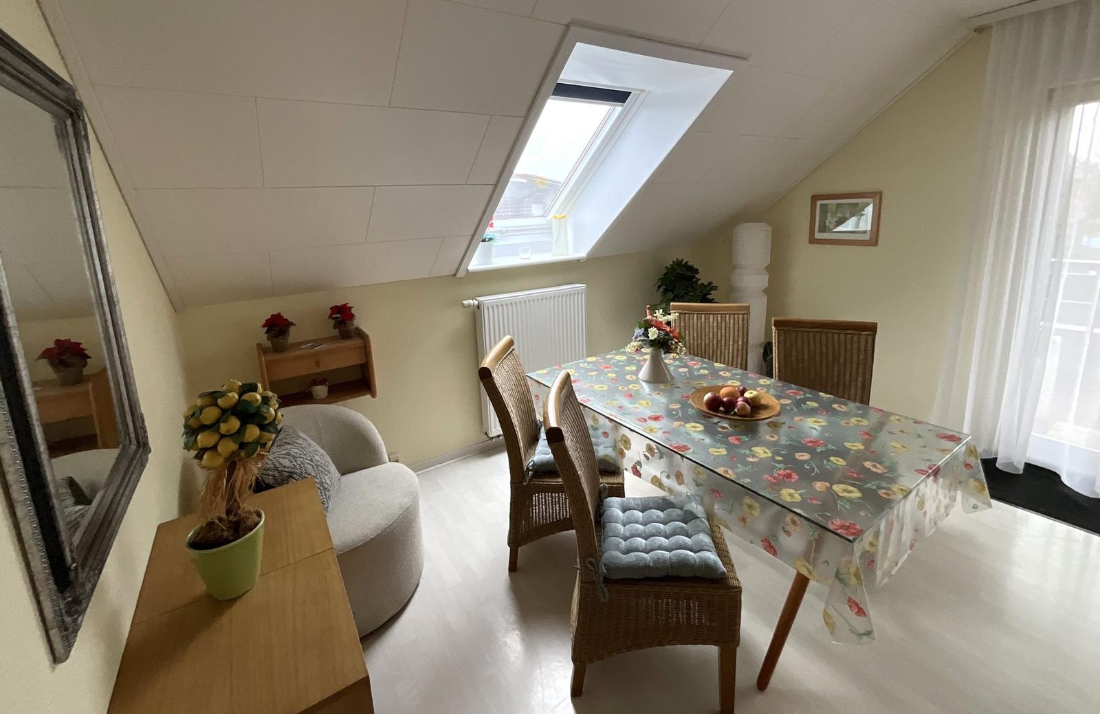 Esszimmer mit Esstisch, Stühlen und Dachfenster. Wandspiegel und Pflanzen sichtbar.