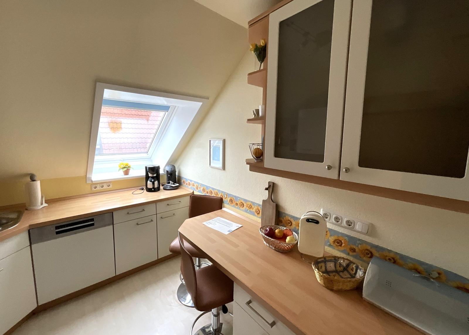 Küche mit Essbereich, Dachfenster und Schränken.
