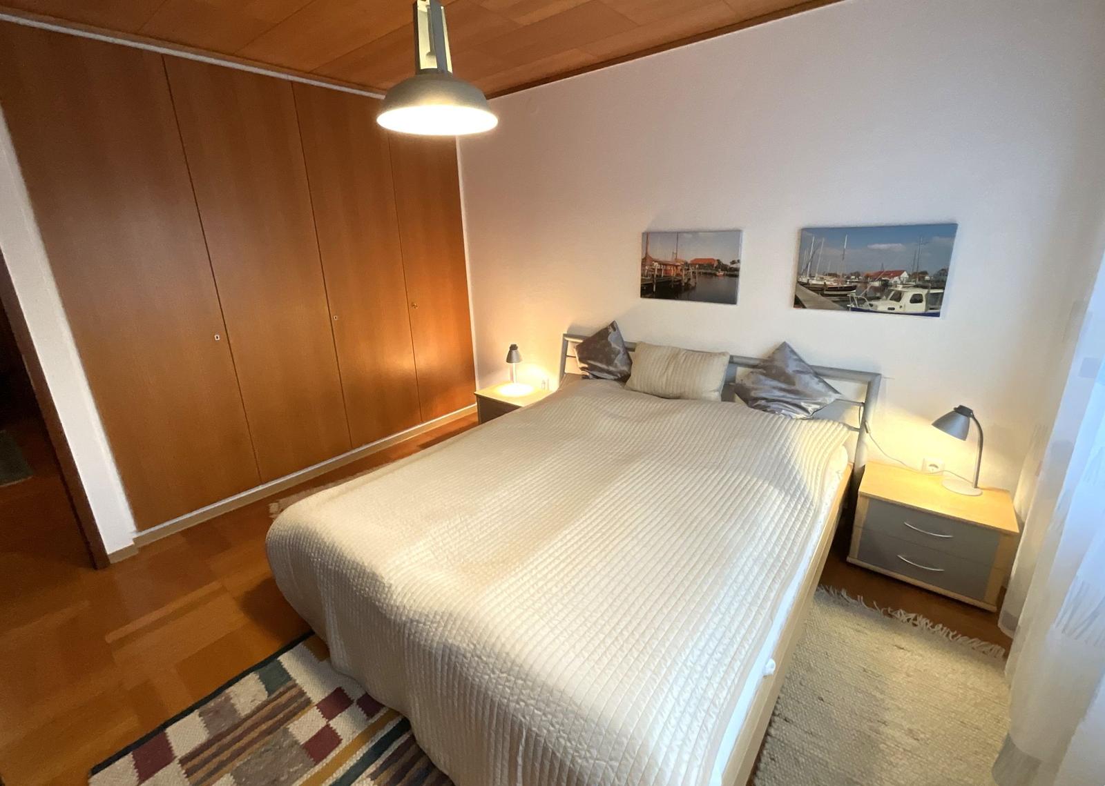 Schlafzimmer mit Bett, Nachttischen und Wandbildern