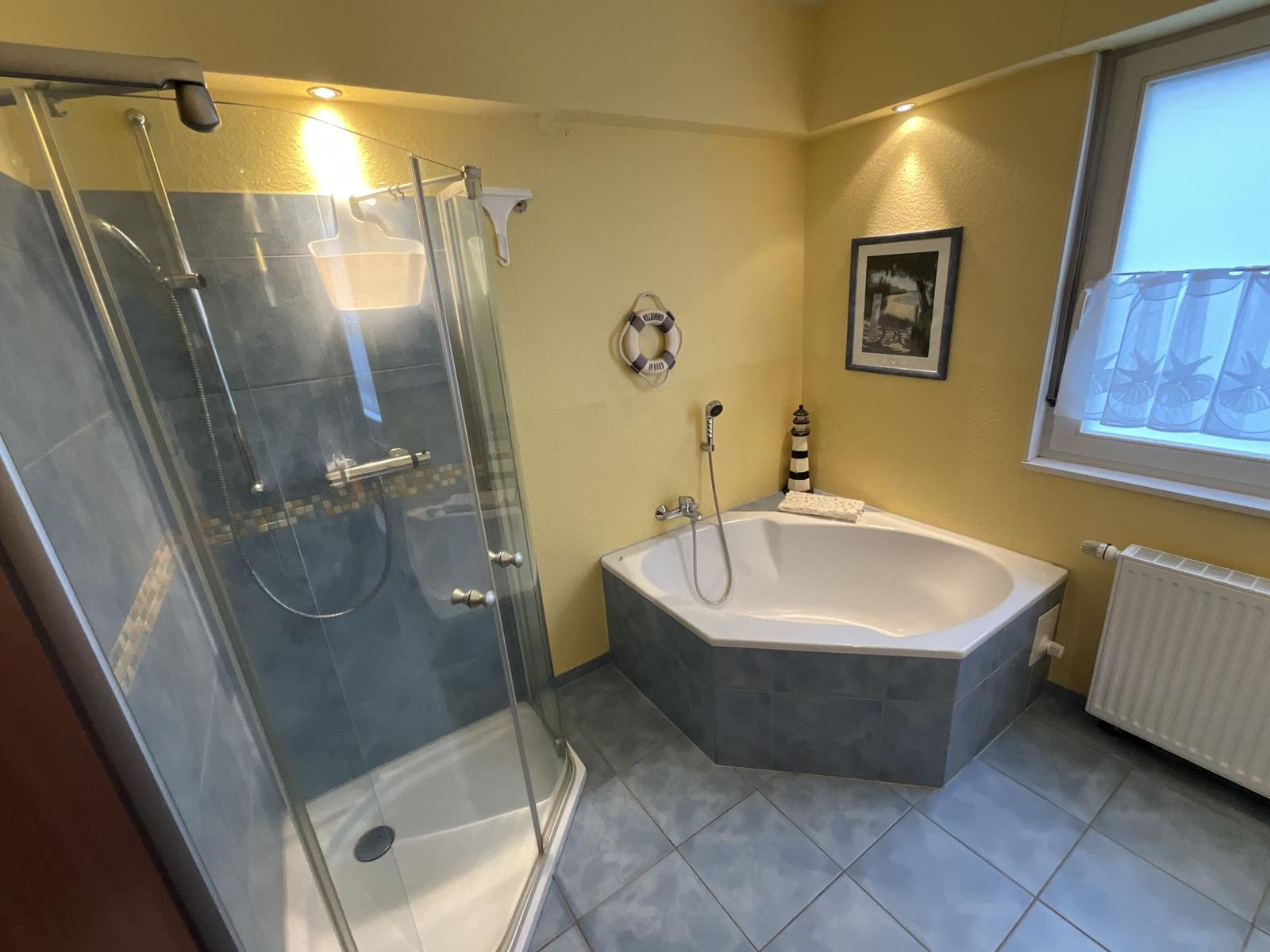 Bad mit Dusche und Badewanne, gelbe Wände, Fenster mit Vorhang.