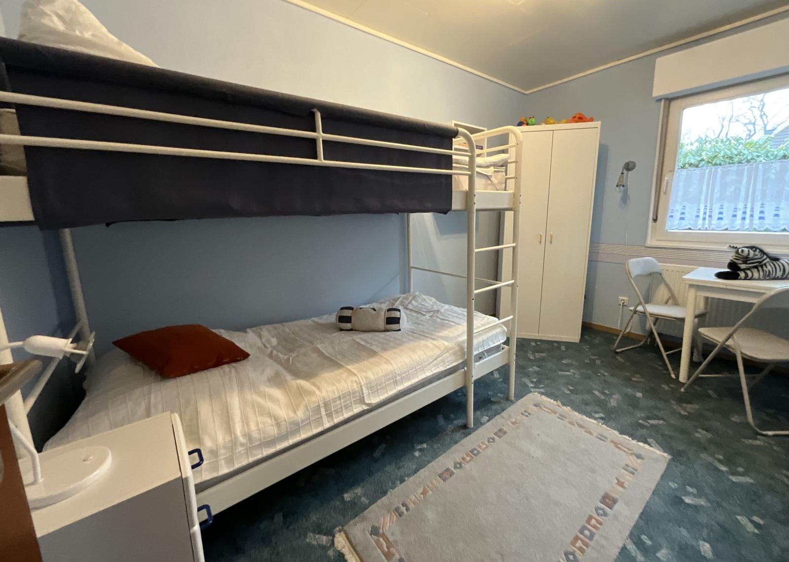 Zimmer mit Doppelstockbett, Schreibtisch und Kleiderschrank.