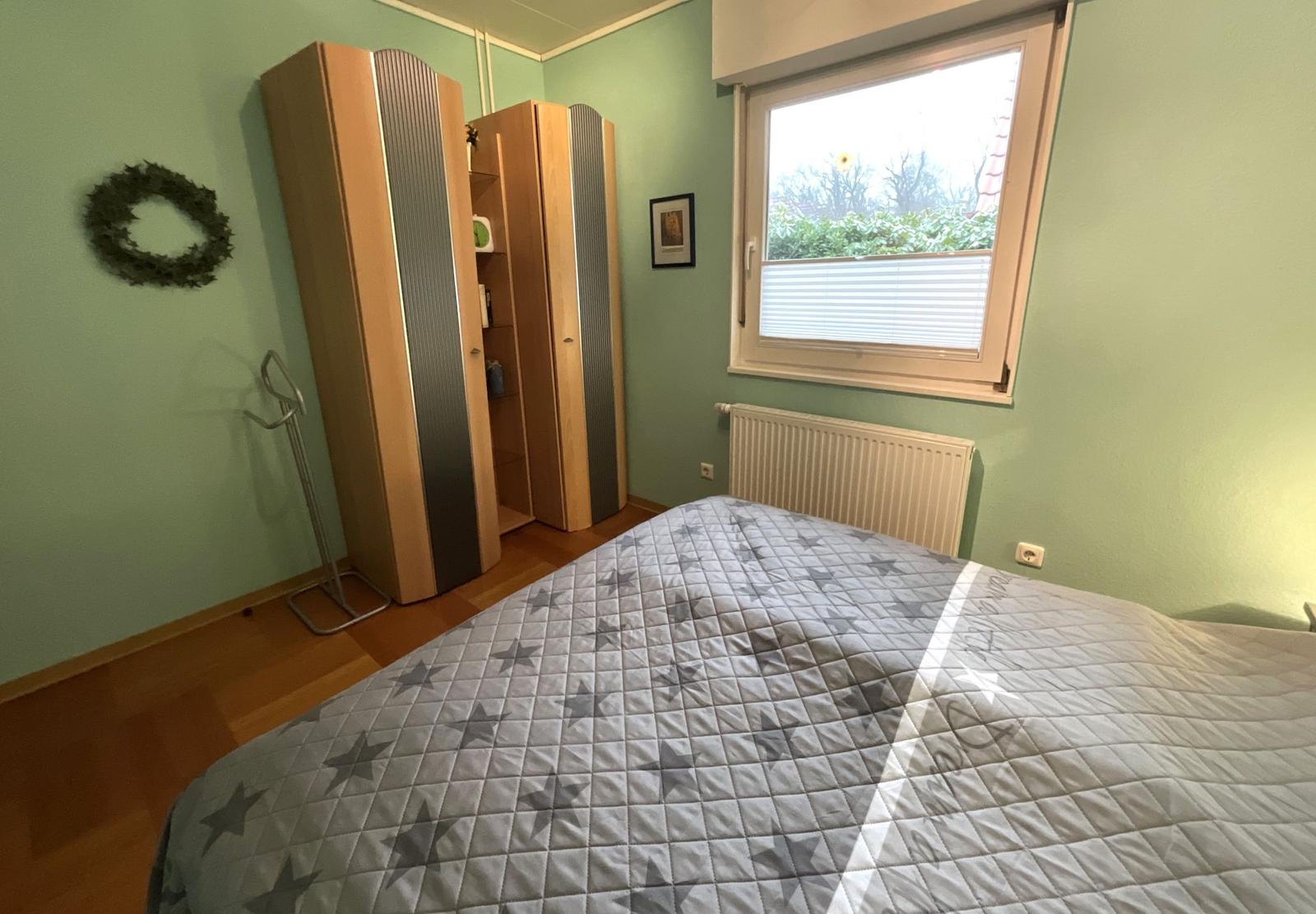 Schlafzimmer mit Bett, Kleiderschränken und Fenster.