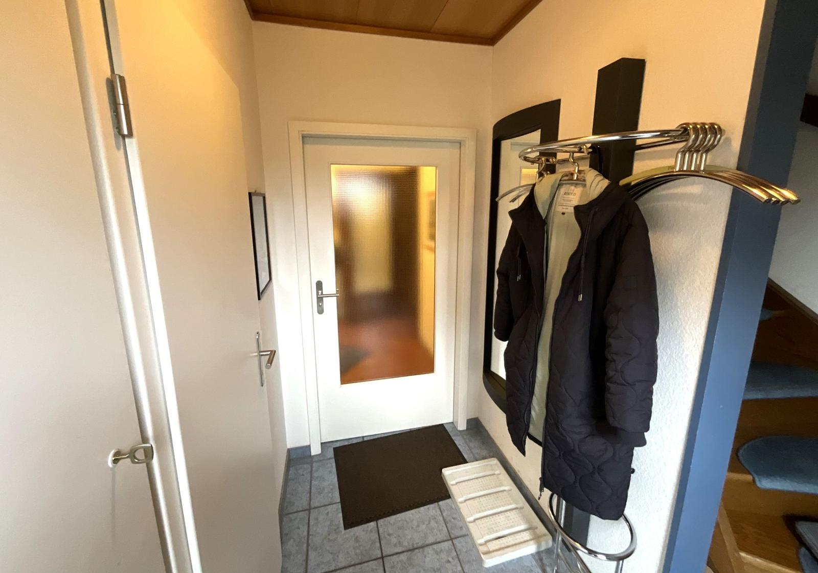 Eingangsbereich mit Garderobe, Schuhe und Tür zum Haus.