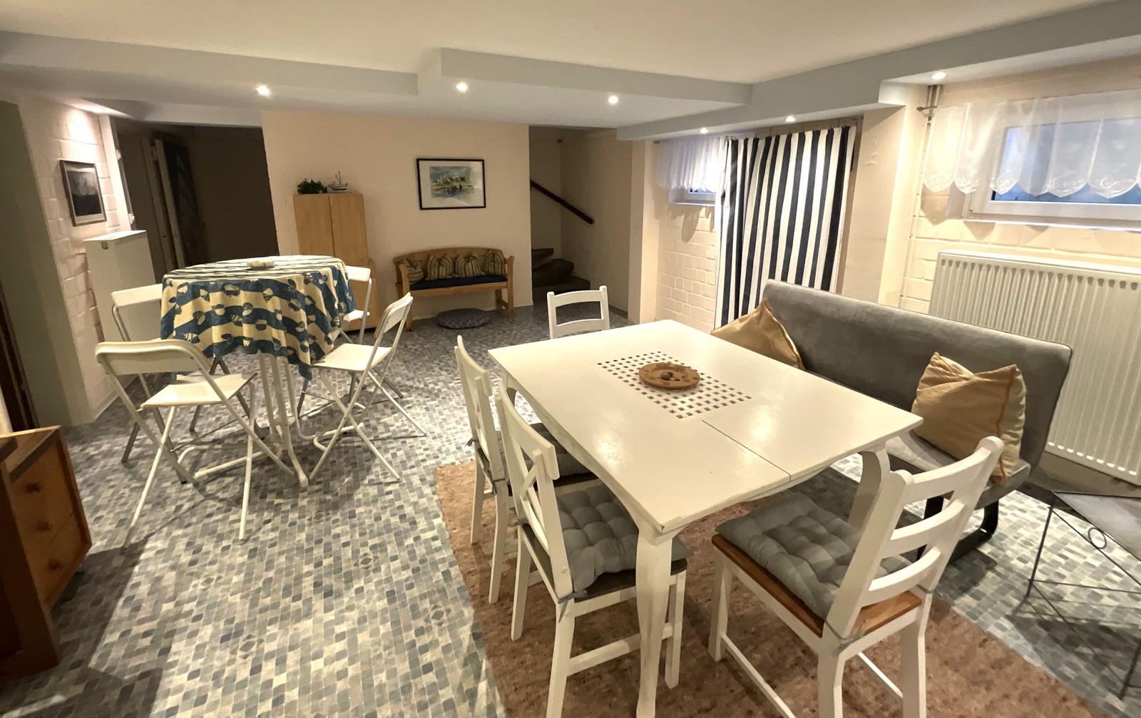 Esszimmer mit weißem Tisch und Stühlen, Sofa und Fenster mit Vorhängen.